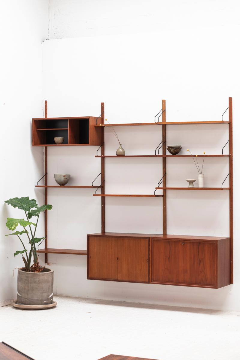 A 3-piece wall unit designed by Poul Cadovius, produced in Denmark in the 1950s. This shelving unit in teak wood is a modular system which allows you to hang the configuration of shelves and cabinets as desired. This set features one shelf of 30cm