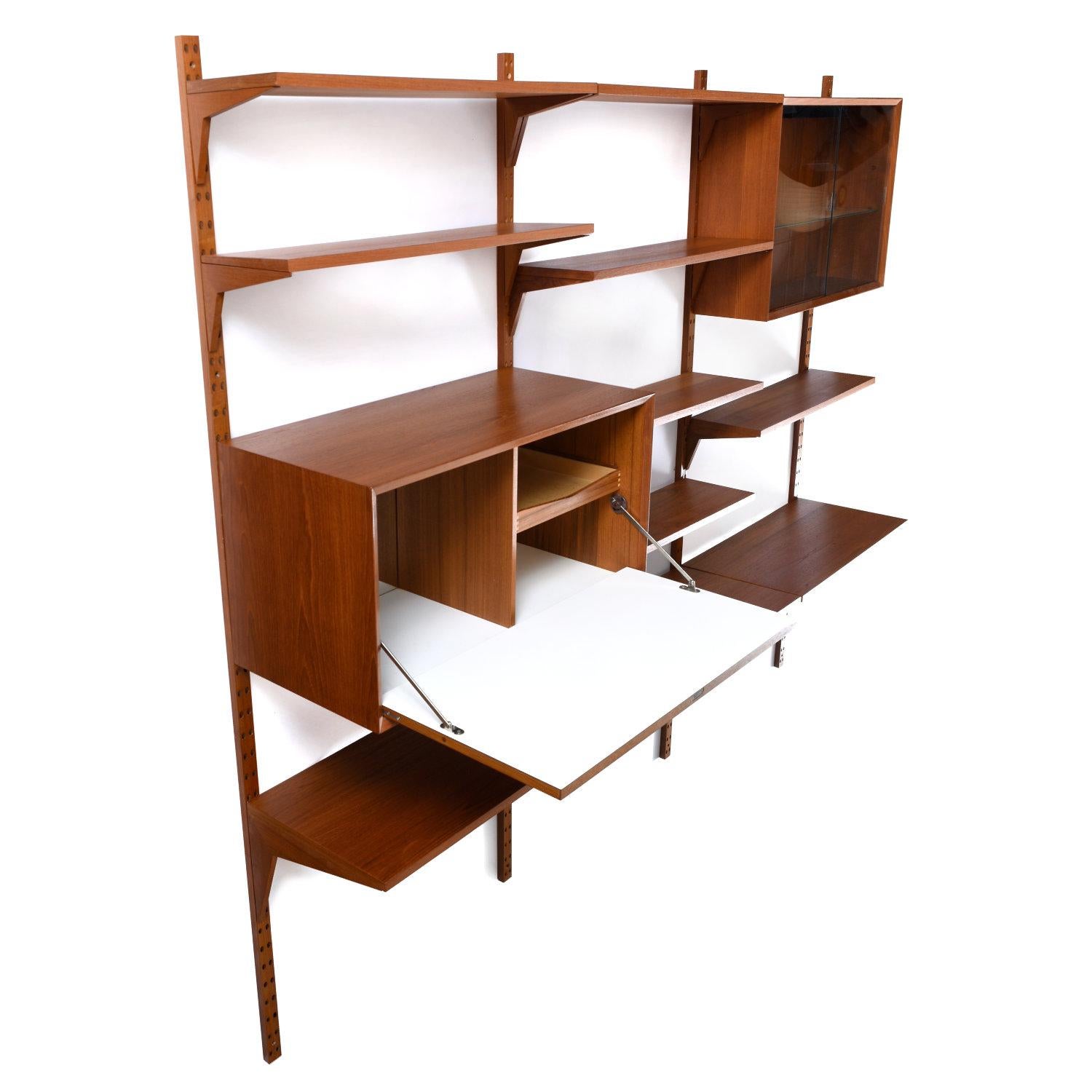 Vintage 1960s Danish teak CADO wall shelving system with modular components. The ingenious design allows one to easily customize a shelving and storage display. Mount the four support poles to the wall. All of the shelves and cabinets effortlessly