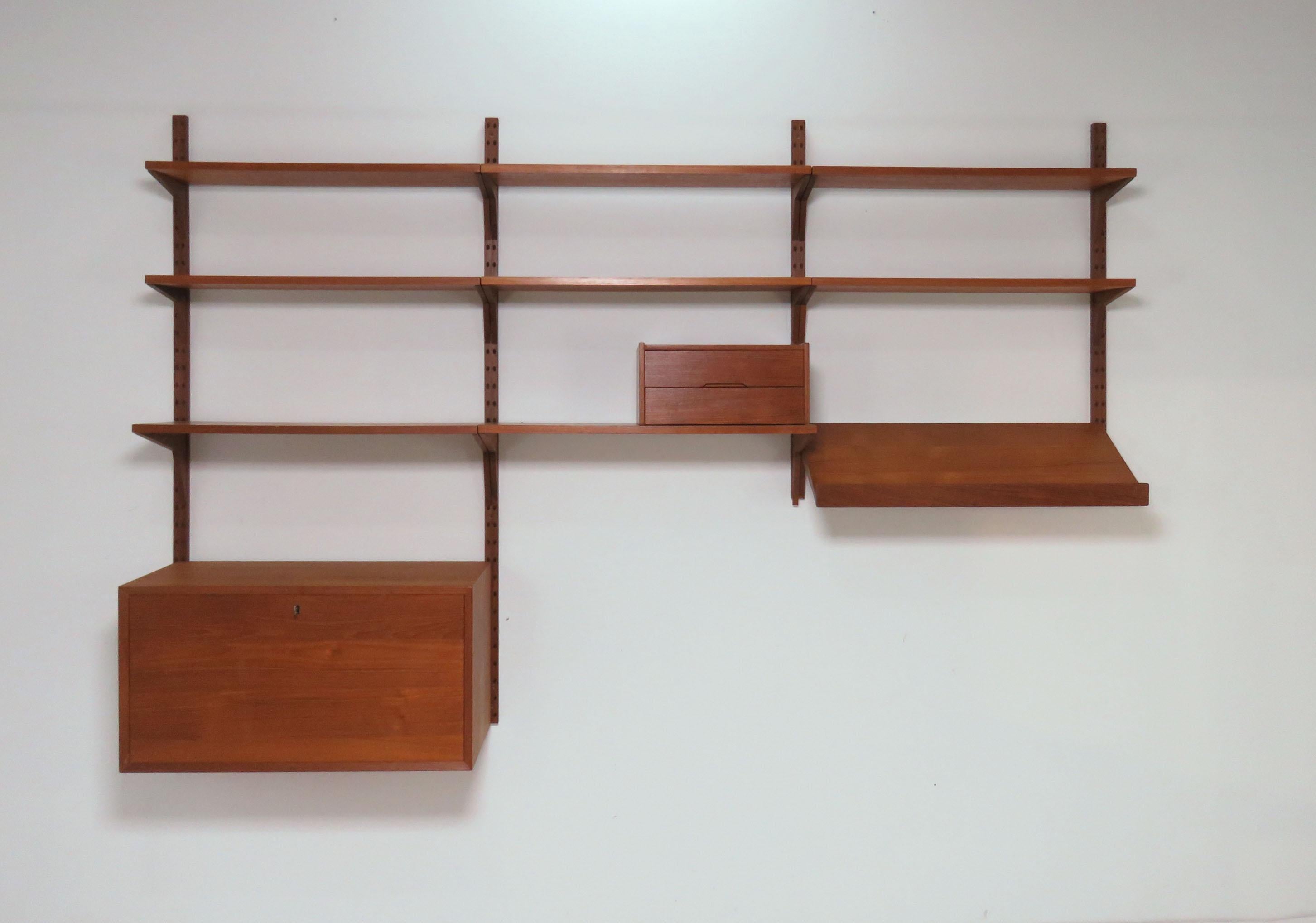 Danish teak three bay wall unit by Poul Cadovius, circa 1960s. Consists of a cabinet with drop down door front (and key), a slanted lipped display shelf, and eight book shelves. Includes a two-drawer letter box in teak by Aksel Kjersgaard odder.