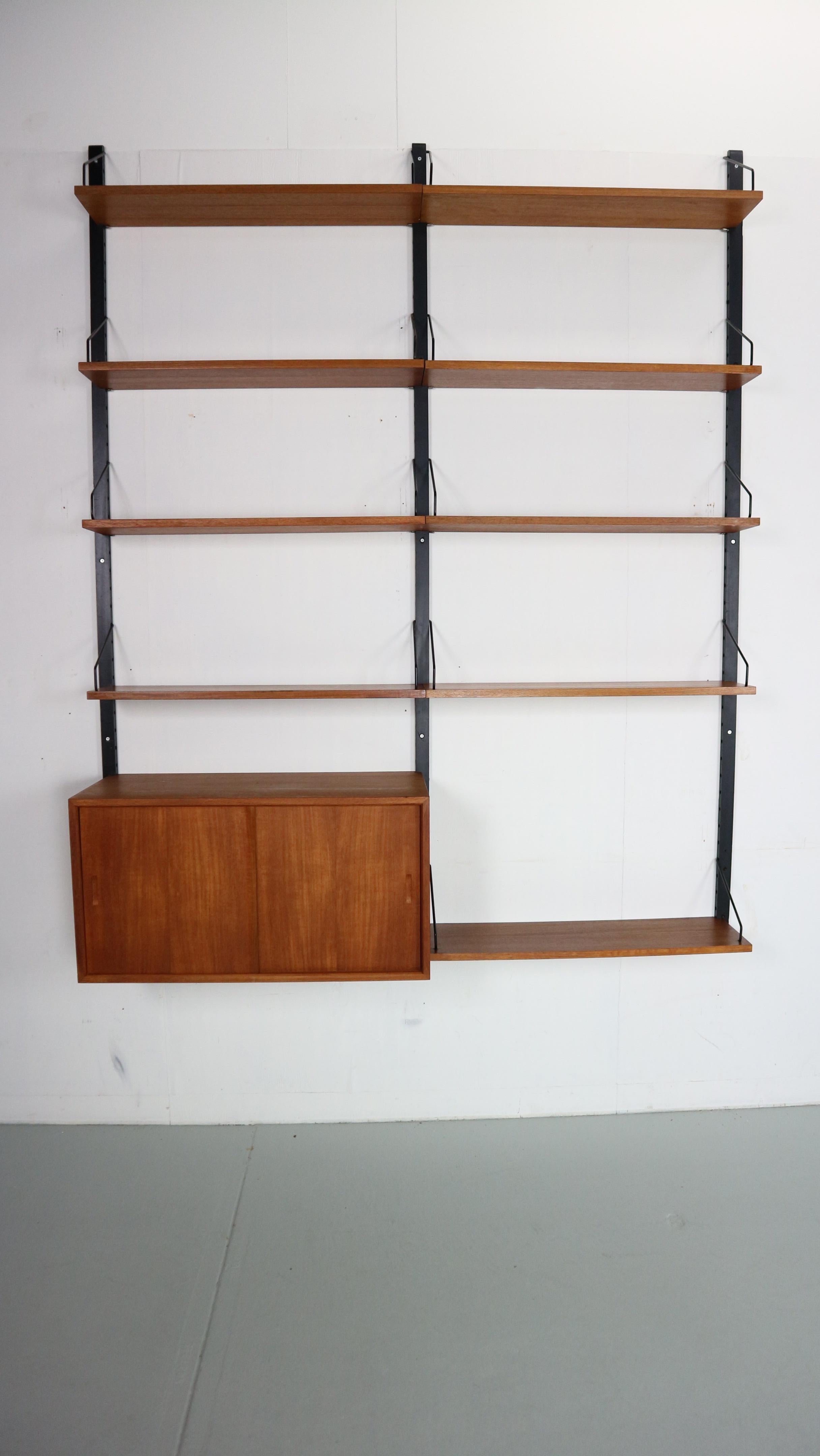 Danish modern teak wall unit designed by Poul Cadovius, Denmark, circa 1960s.

This piece is contains of 9 shelves and one cabinet with sliding doors.

This piece is completely adjustable, and any of the case pieces or shelves can be installed