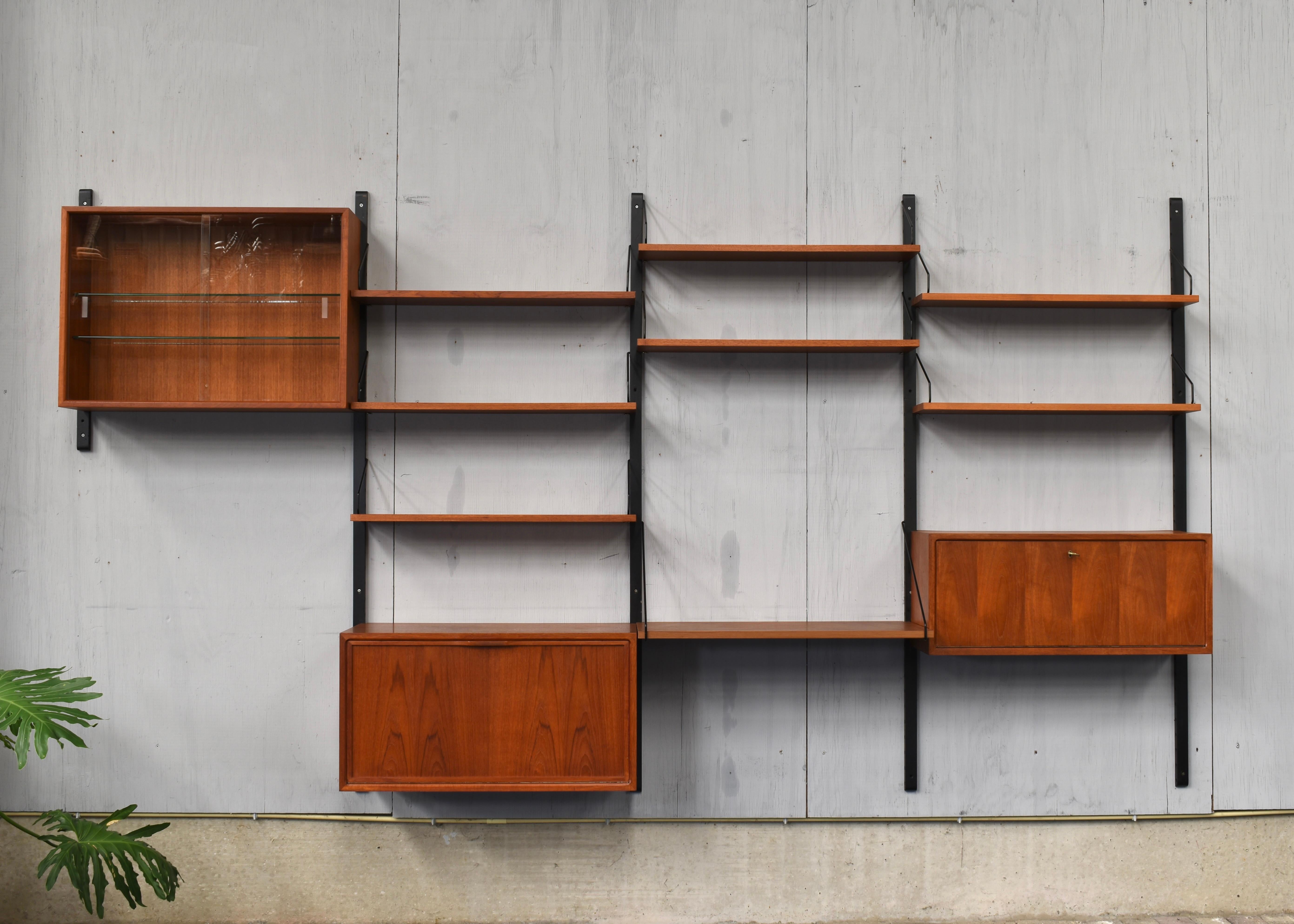 Modular Teak wallmounted wall-unit by Poul Cadovius for CADO, Denmark - circa 1950.
The wall unit includes a liquer cabinet with curved glass shelve so it can place bottles like whiskey or cognac inside. Glasses go on top of the curved glass