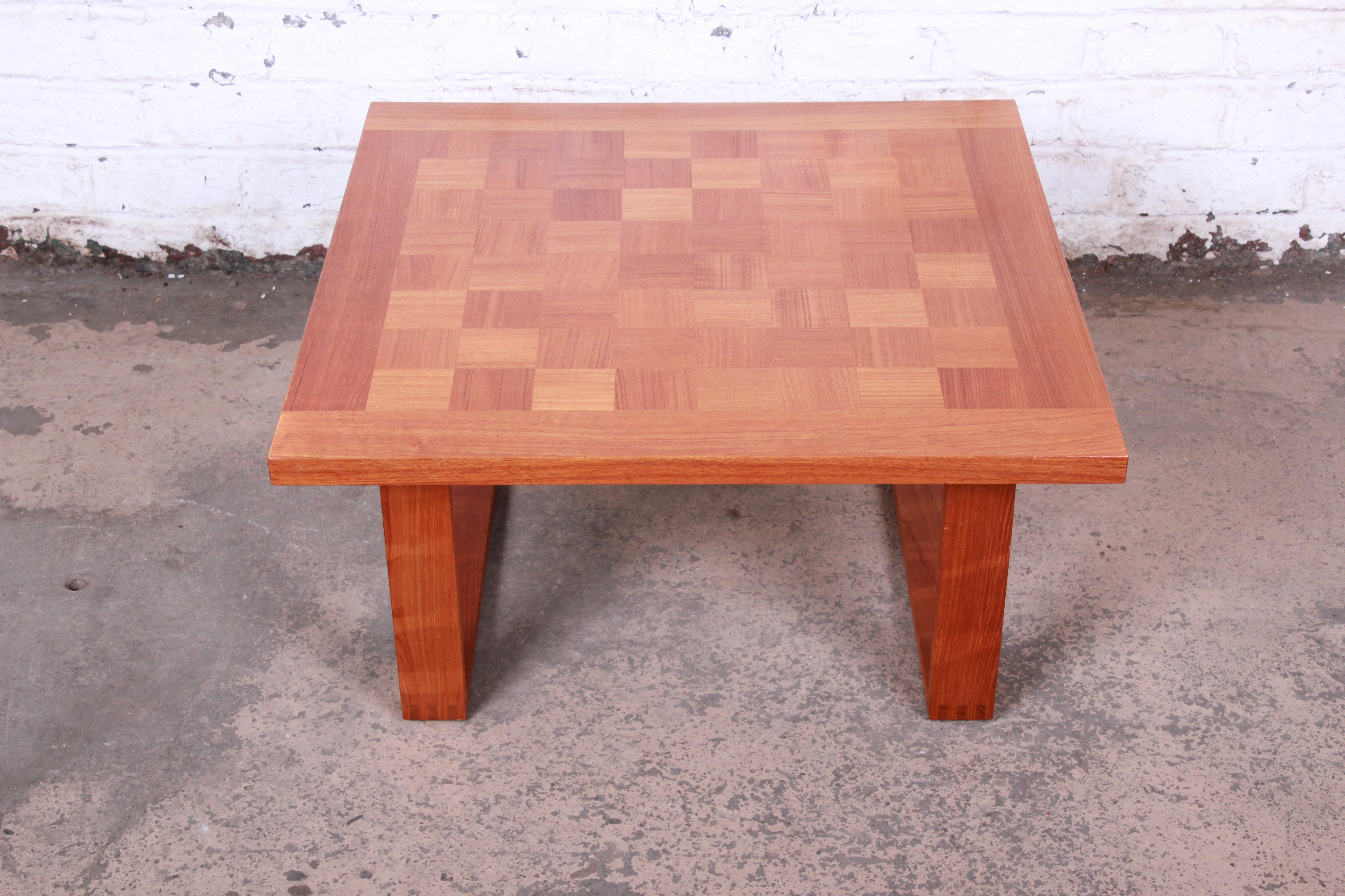 A gorgeous midcentury Danish Modern teak coffee table by Poul Cadovious for France & Son. The table features beautiful teak wood grain with an inlaid checkerboard design on top and exposed dovetail joints on the legs. The original label is present