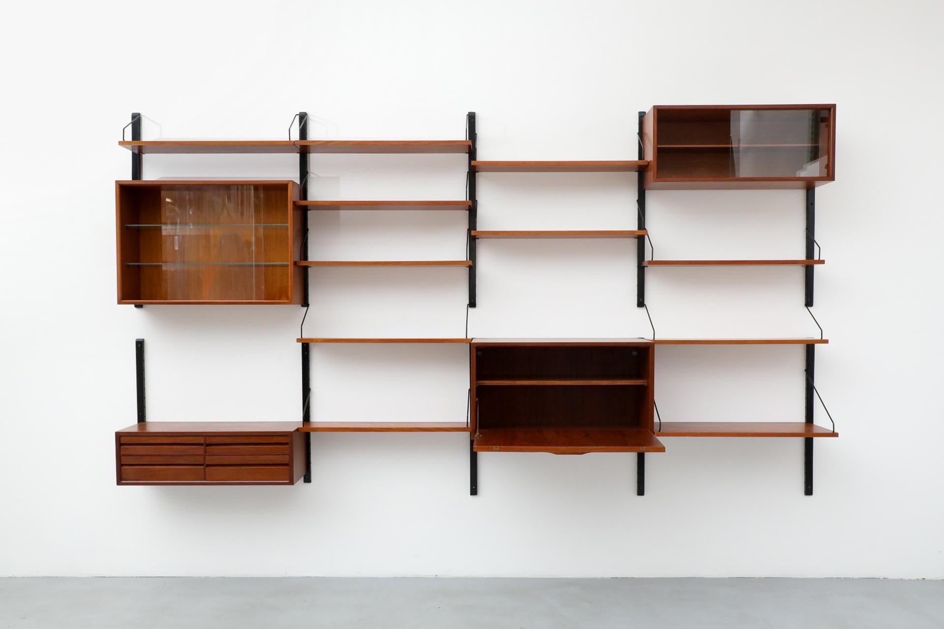 Stunning, 1960's four section Royal System by Poul Cadovius. Wall mounted unit with drop-down desk cabinet including a key, multiple shelves, drawer storage, and cabinets with sliding glass doors. Minimalistic, versatile and practical with gorgeous