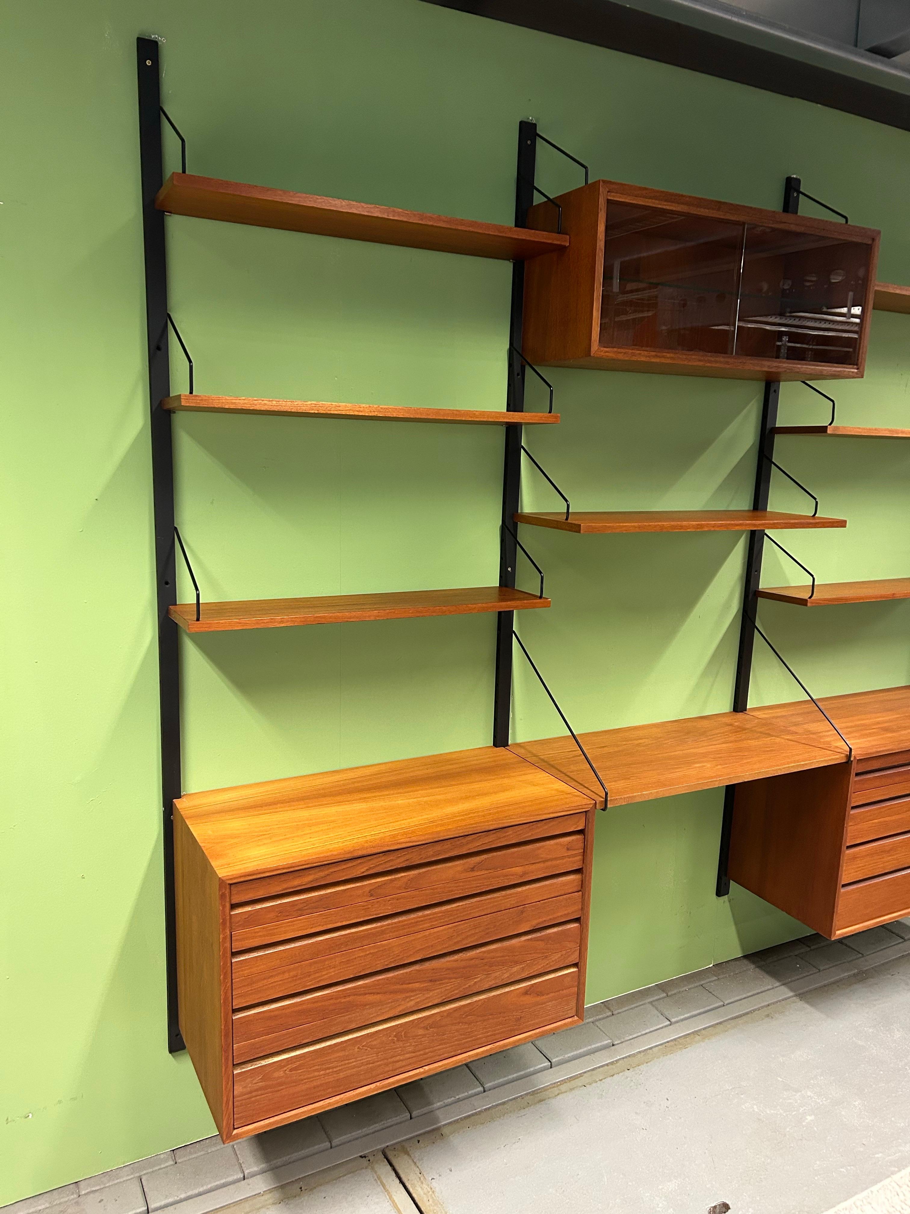 Danish modern teak wall unit designed by Poul Cadovius, Denmark, circa 1960s.

This piece is contains 8 shelves, six are 20cm deep one is 30cm and one is 40cm, two drawer cabinets drawer cabinet and a display cabinet.

This piece is completely