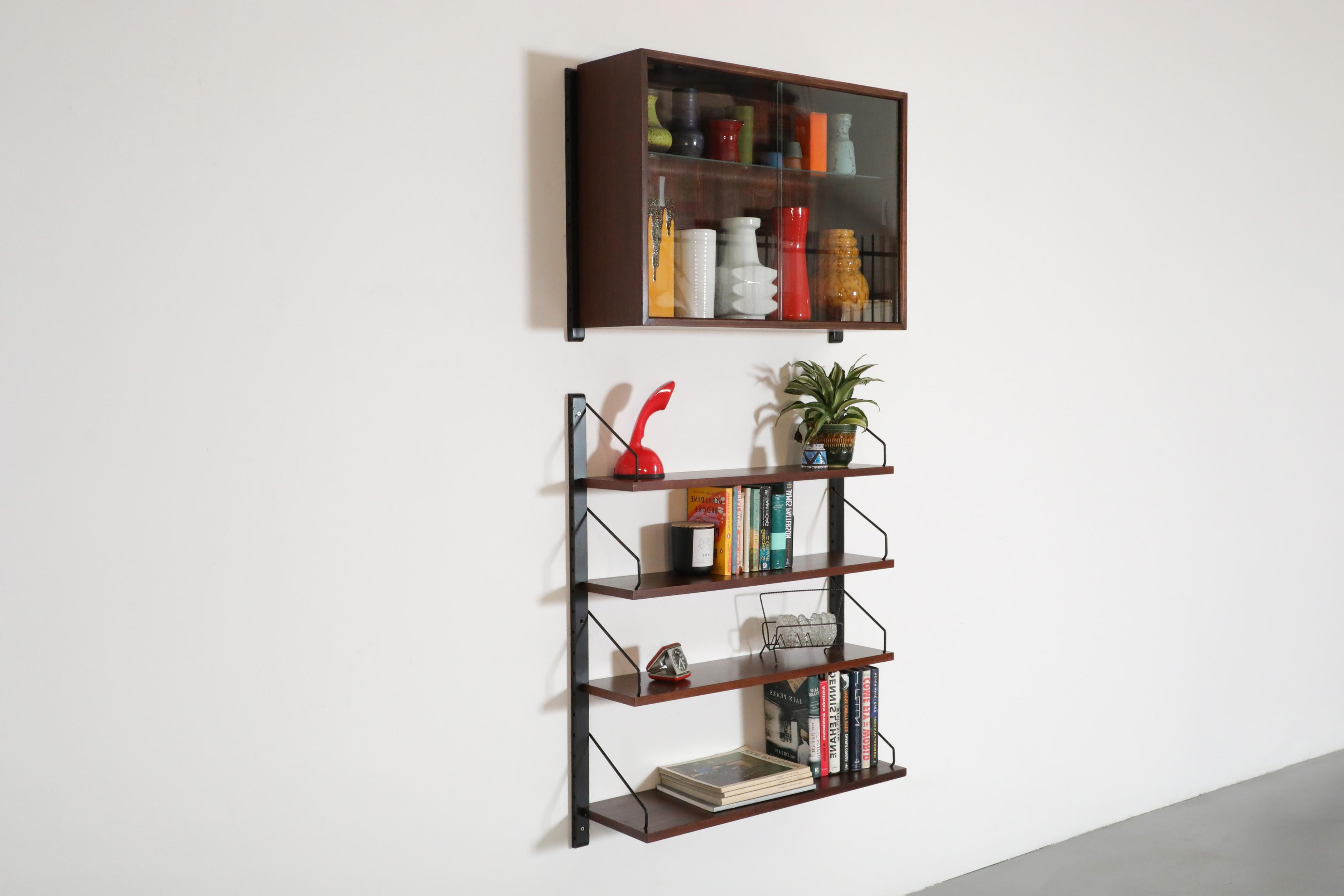 An interchangeable Poul Cadovius rosewood wall mounted Royal System with shelving, black risers and a cabinet with glass doors and shelf. This can be a multi-section unit as well. The cabinet (32.125