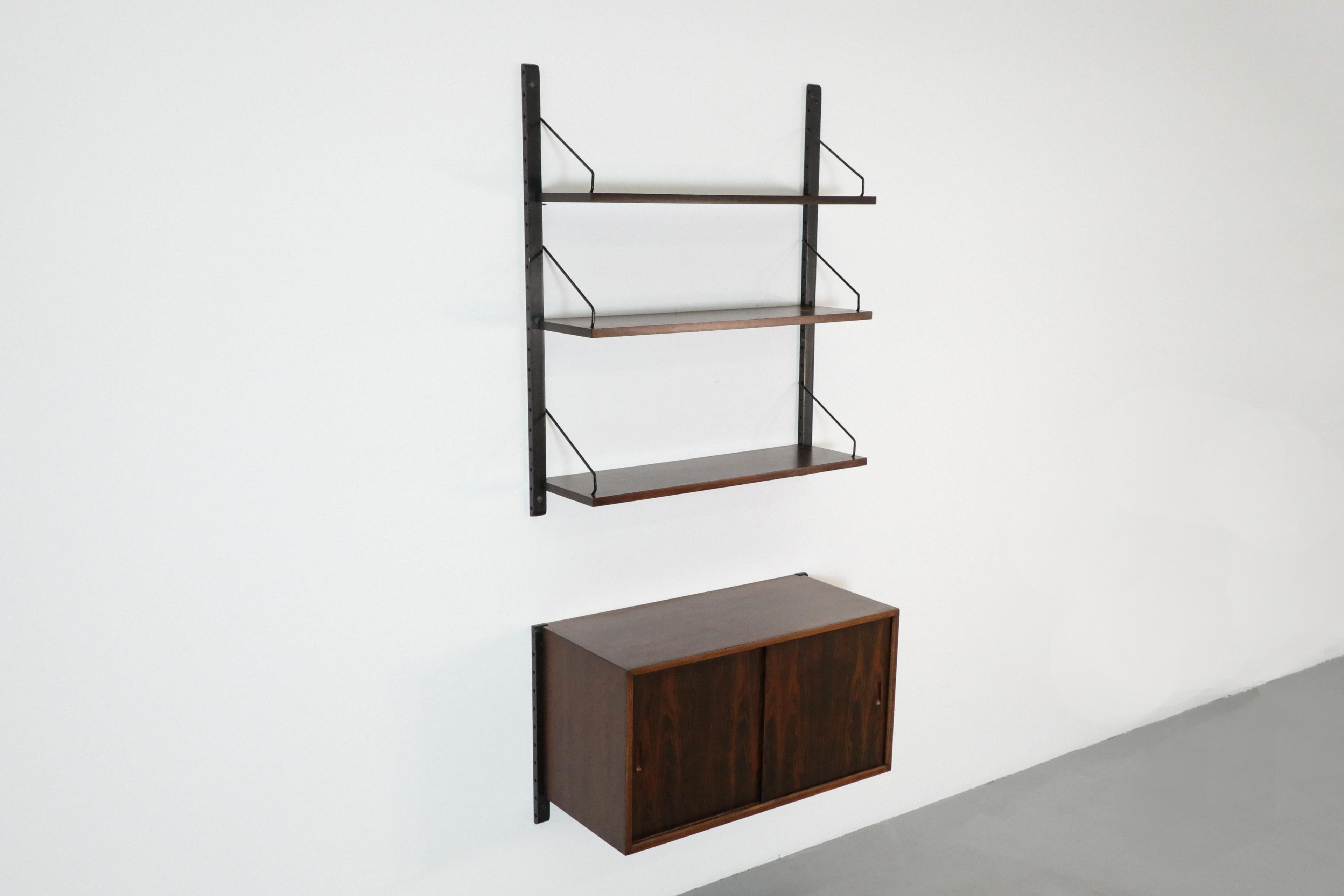 Poul Cadovius Royal Shelving Rosewood wall mount shelving unit and cabinet. The top shelves have black wood risers with rosewood shelves, the cabinet can be mounted above or below, has sliding doors and a cutout in the back for cords. Total