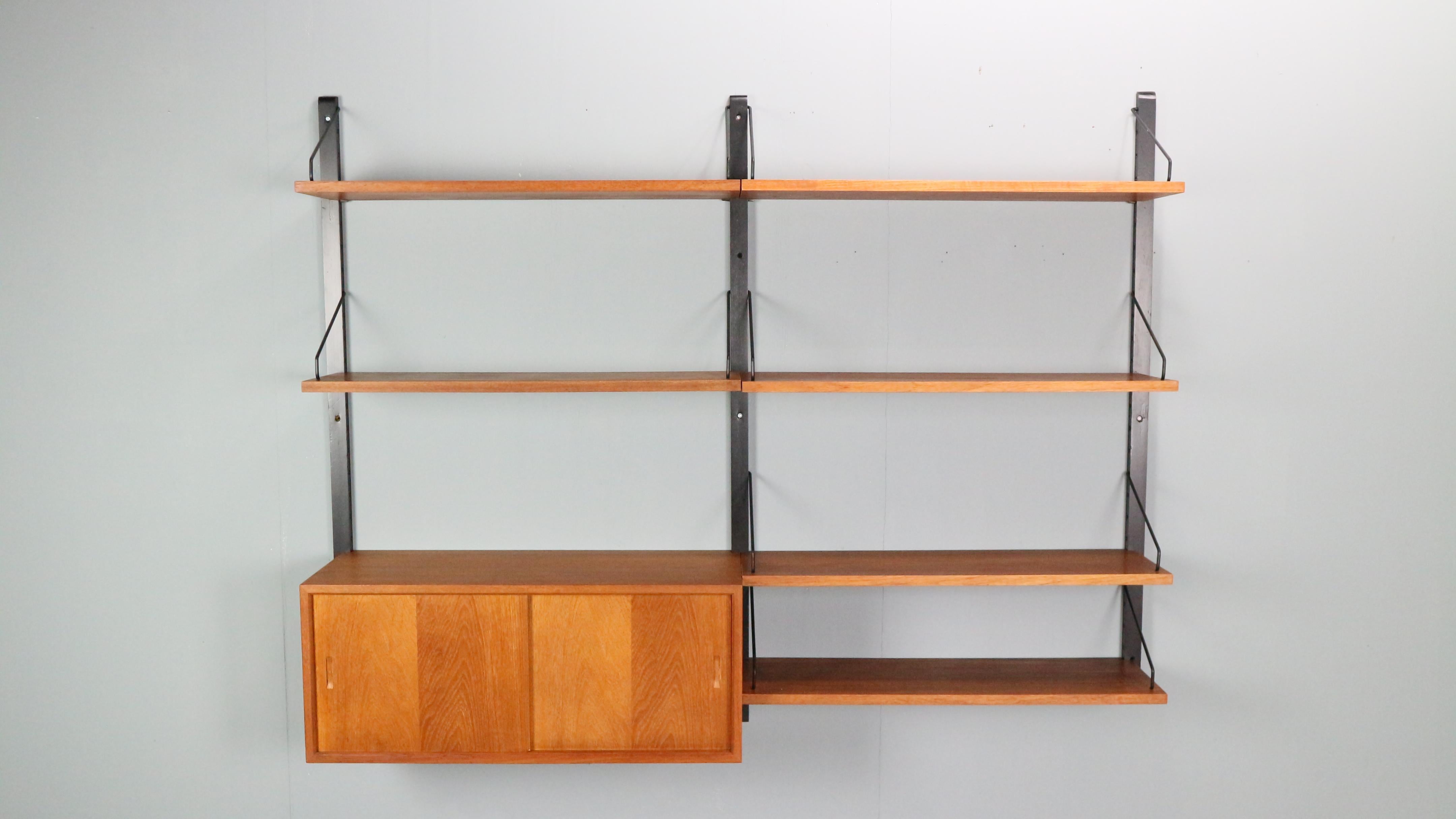 Danish modern teak wall unit designed by Poul Cadovius, Denmark, circa 1960s.

This piece is contains of 6 shelves and one cabinet with sliding doors.


This piece is completely adjustable, and any of the case pieces or shelves can be installed