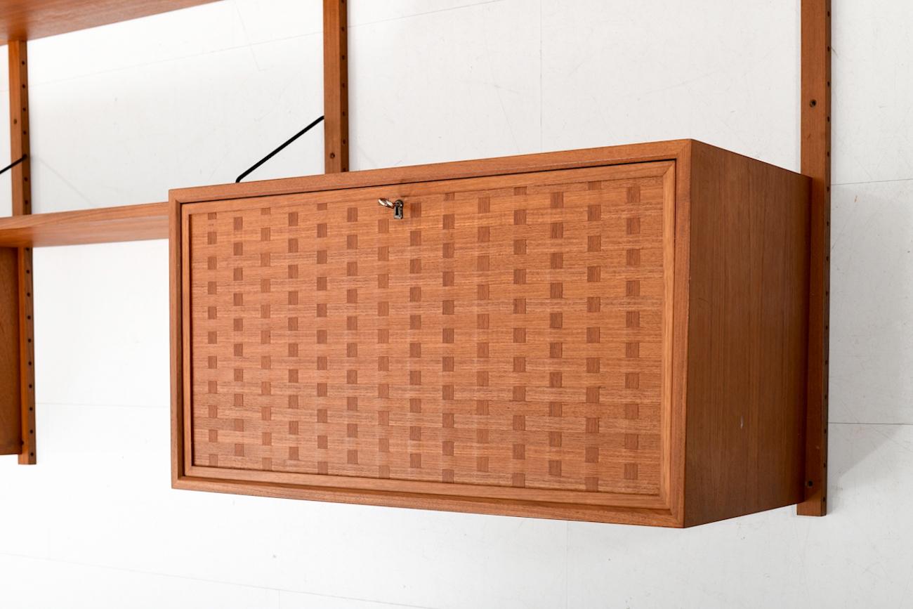 Cado wall system in teak. Royal System. Designed by Poul Cadovius. Manufactured by Cado. - Ten shelves - Three cabinets - Four wall brackets. Very good vintage condition. Ready to hang. Nice teak color.
Size: 38.5 x 244.5 x 198.0 (wall brackets) CM