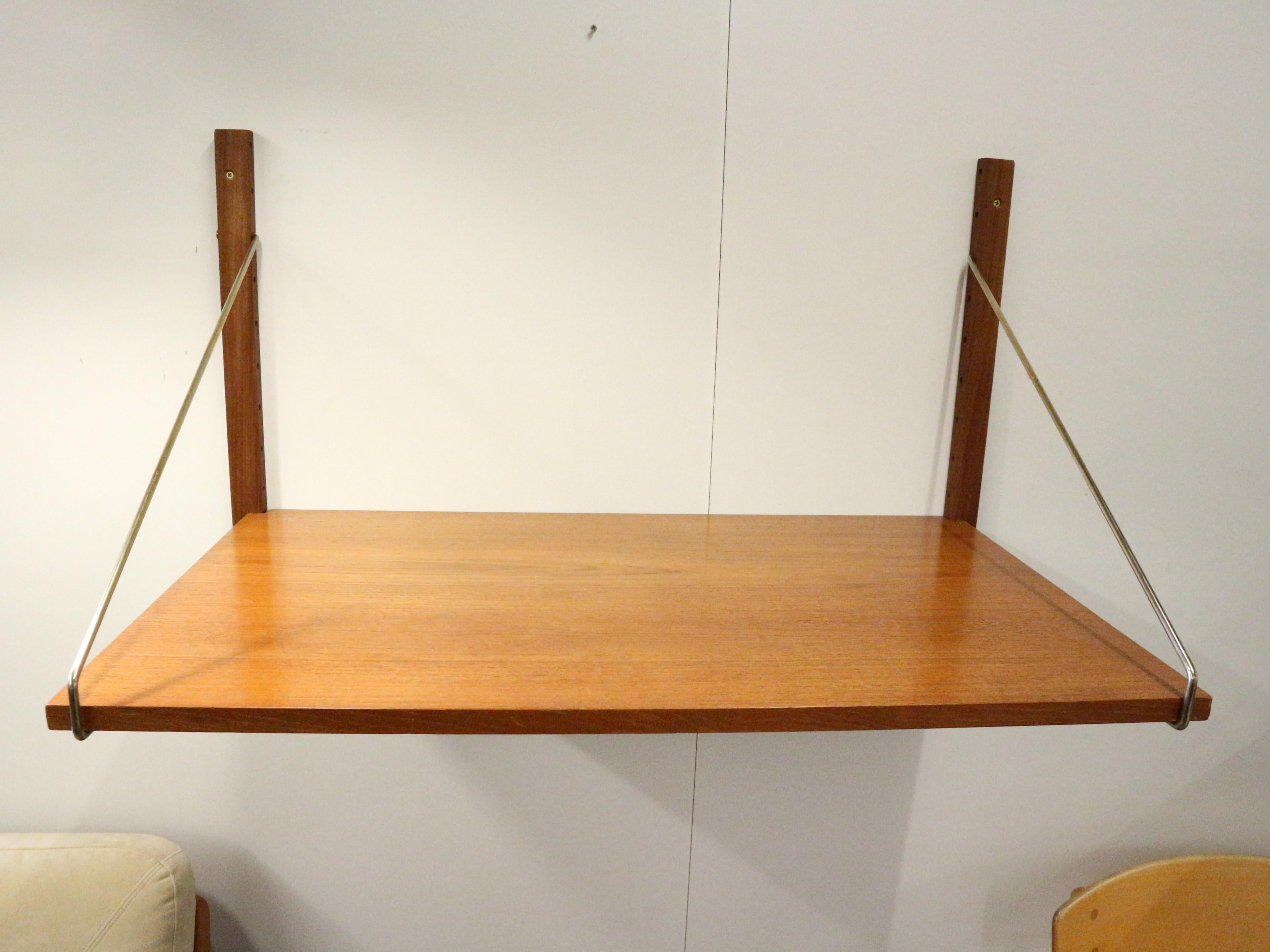 This Mid-Century teak wall-mounted shelving system, made by Danish designer Poul Cadovius . This shelf is mounted on teak risers and brass patinated brackets. 
The shelf can be used as small desktop or to store or display things.