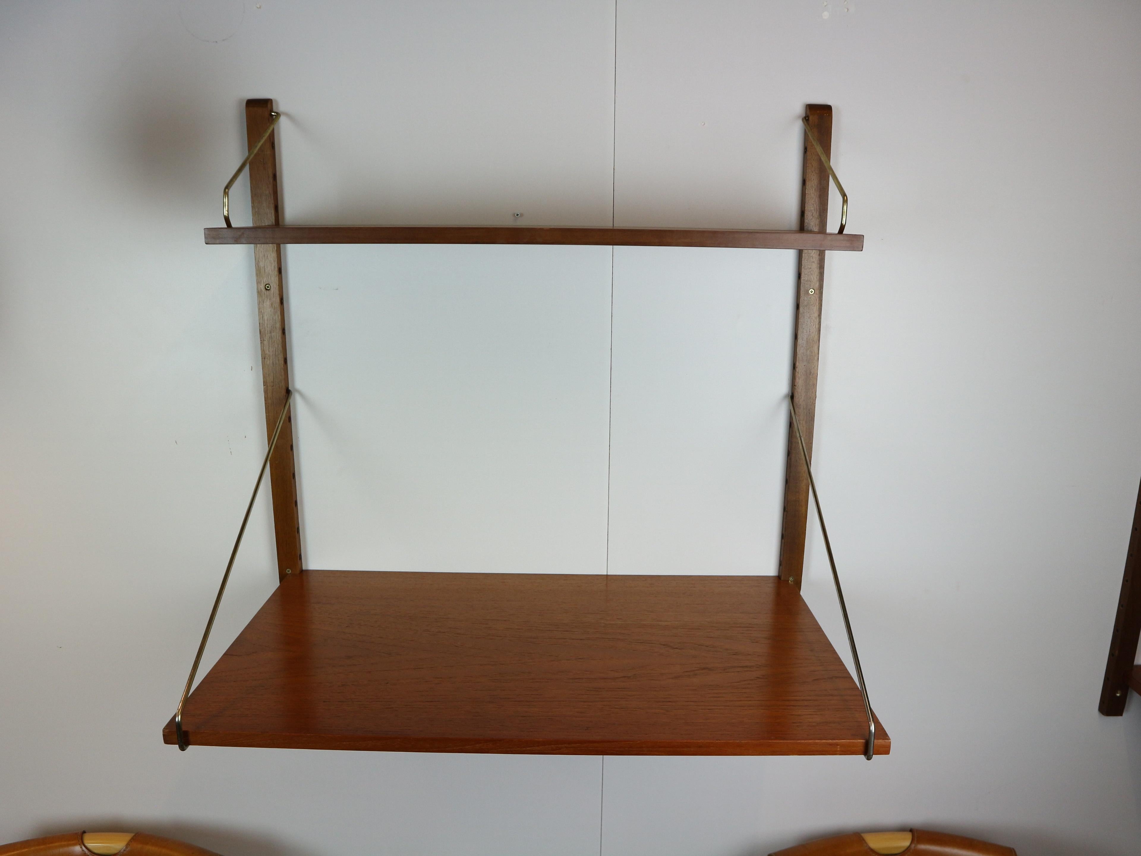 This Mid-Century teak wall-mounted shelving system, made by Danish designer Poul Cadovius . This shelf is mounted on teak risers and brass patinated brackets. 
The shelfs can be used as small desktop or to store or display things.