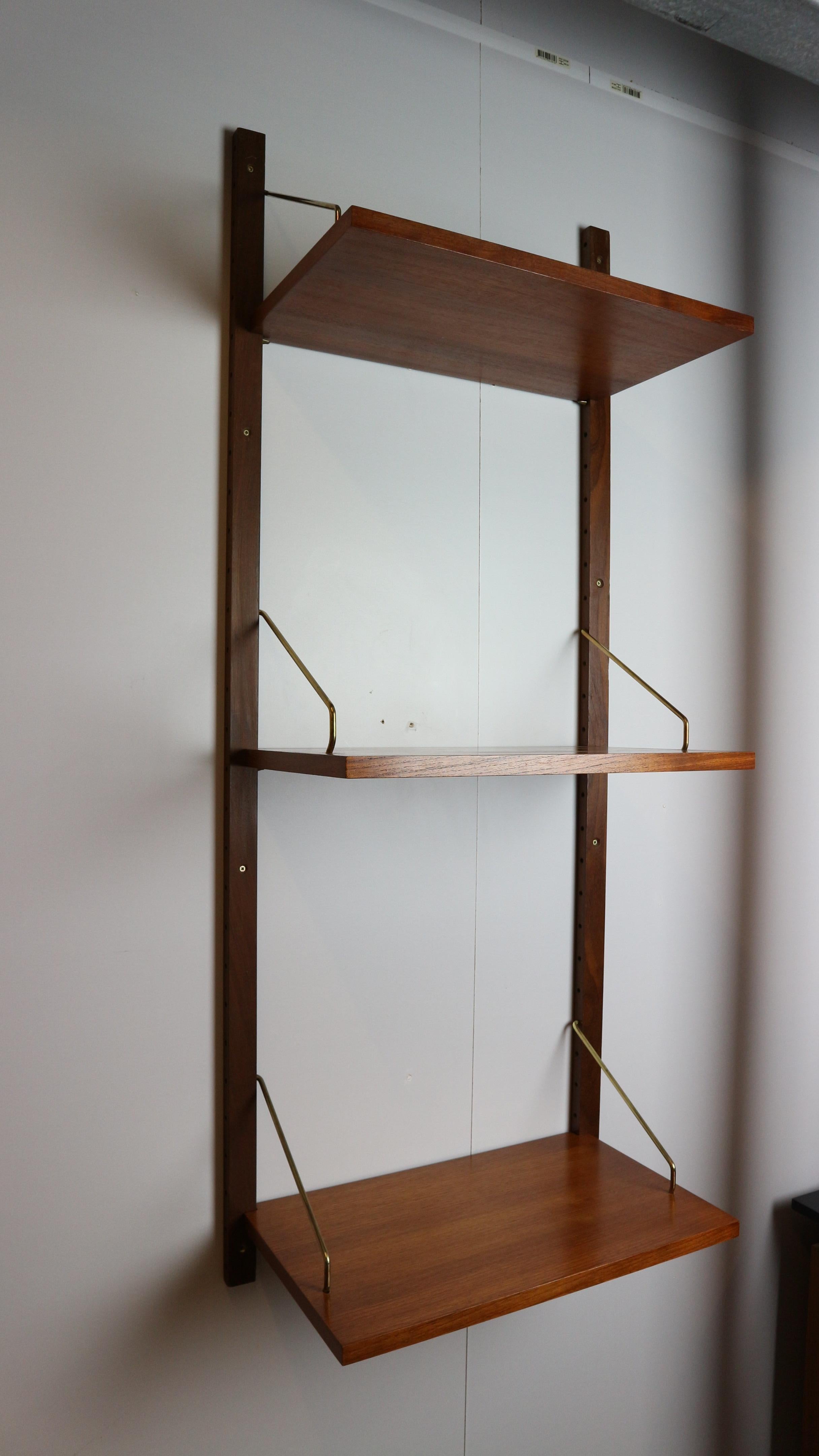 This Mid-Century teak wall-mounted shelving system, made by Danish designer Poul Cadovius has interchangeable shelves mounted on teak risers and brass paginated brackets. 
The shelf can be used for books or other decoration/objects. 