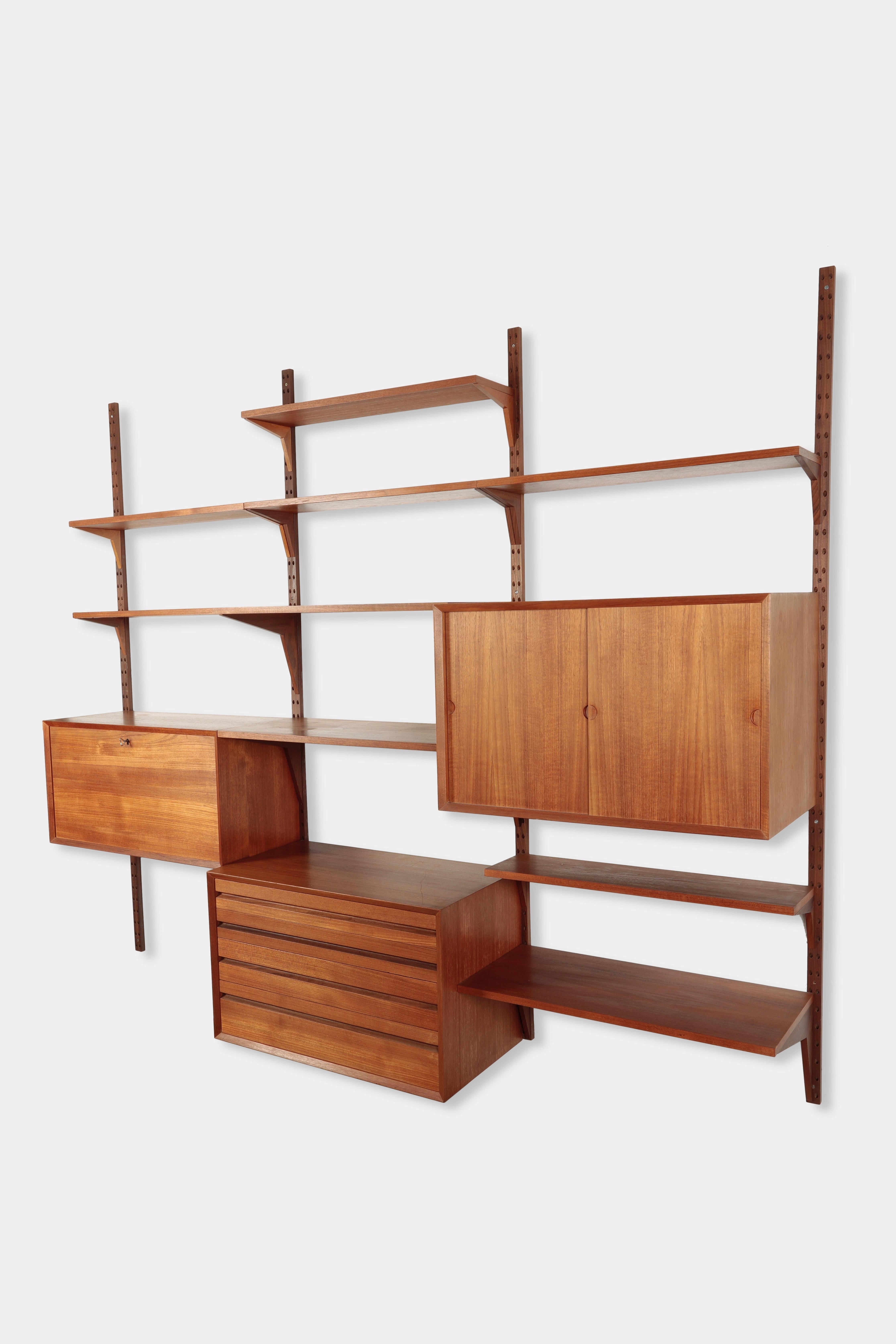 Poul Cadovius “Royal System” wall unit manufactured by Cado in the 1950s in Denmark. Carefuly processed wall unit made of solid teak wood. Three different cabintes with drawers, sliding doors and one hinged door that can be used as a desk and nine