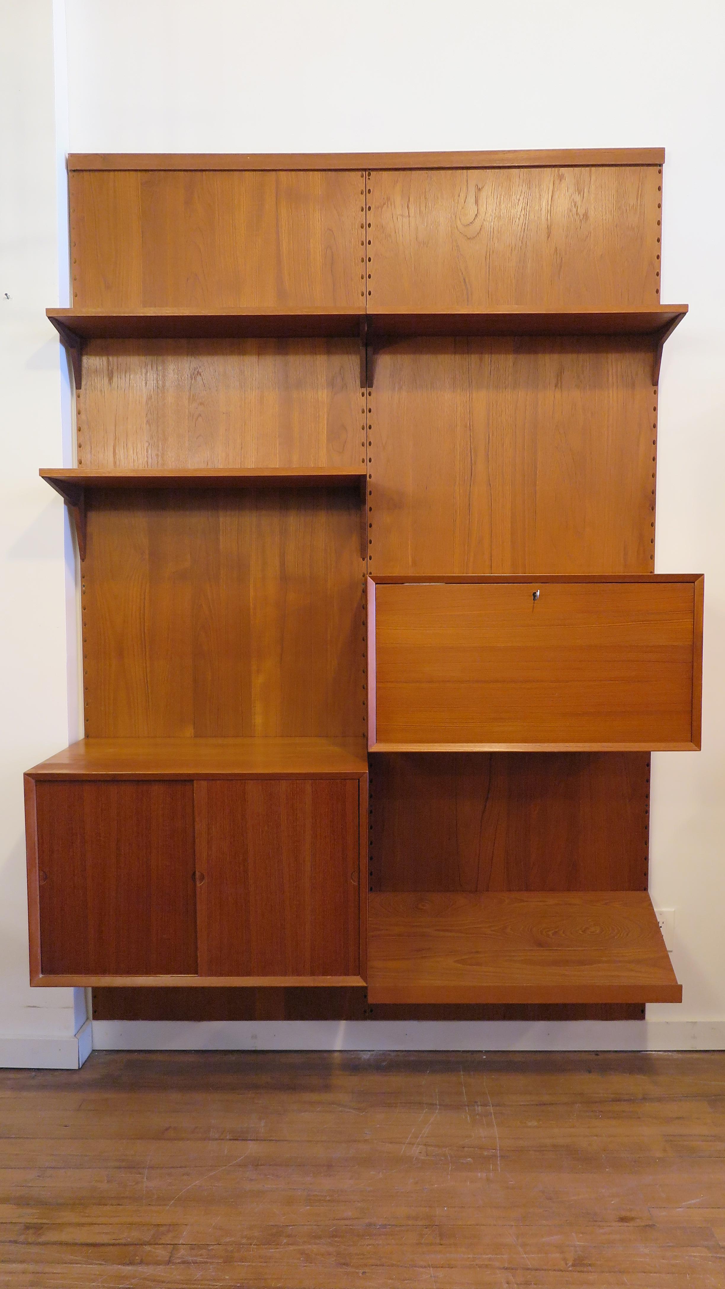 Poul Cadovius Royal Systems wall unit for Cado. Two Teak panels with adjustable shelves, cabinet, dry bar, and magazine rack. Three book - display shelfs, a cabinet having two adjustable height drawers, a dry bar cabinet with mirrored back, single
