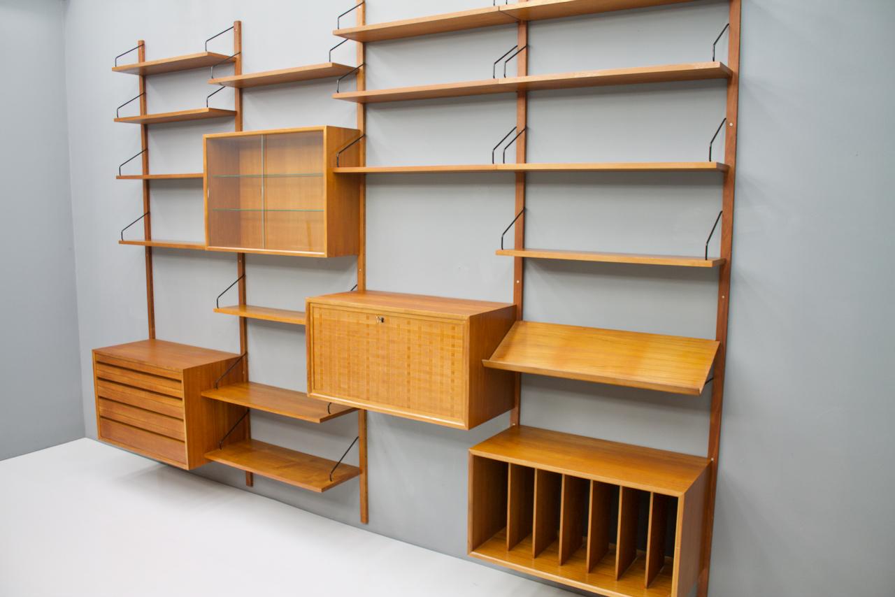 Large teak wood wall system 'Royal' by Poul Cadovius for Cado, Denmark 1956

1 x teak cabinet with 4 drawers
1 x teak vitrine with two glass doors 
1 x teak cabinet, desk
1 x Teak cabinet
2 x shelves 80 x 30 cm. 
13 x shelves 80 x 20 cm. 
1