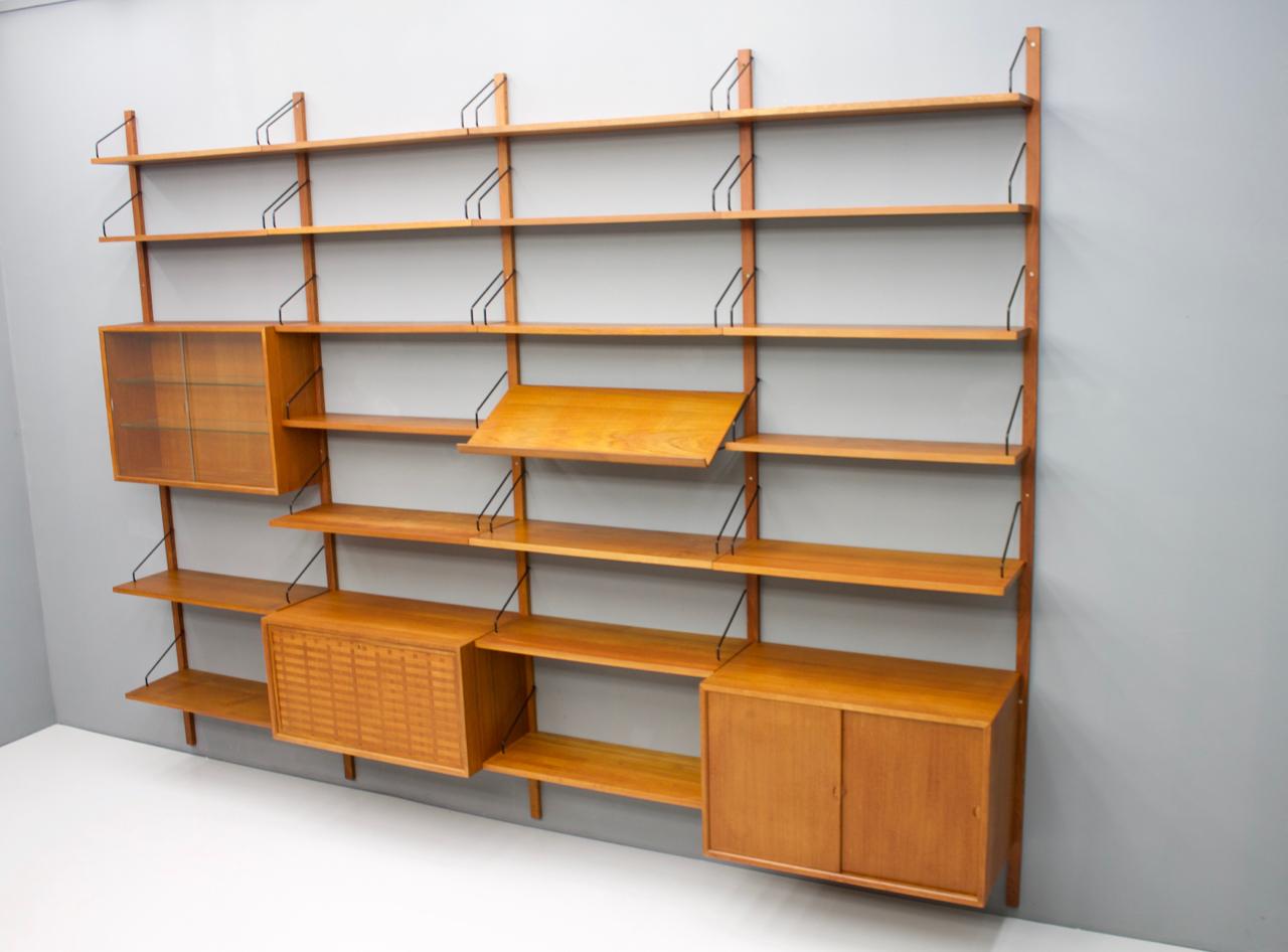 Large teak wood wall system 'Royal' by Poul Cadovius for Cado, Denmark, 1956
1 x teak cabinet with 2 sliding doors
1 x teak vitrine with two glass doors
1 x teak cabinet, dry bar
4 x shelves 80 x 30 cm.
16 x shelves 80 x 20 cm.
1 x magazine