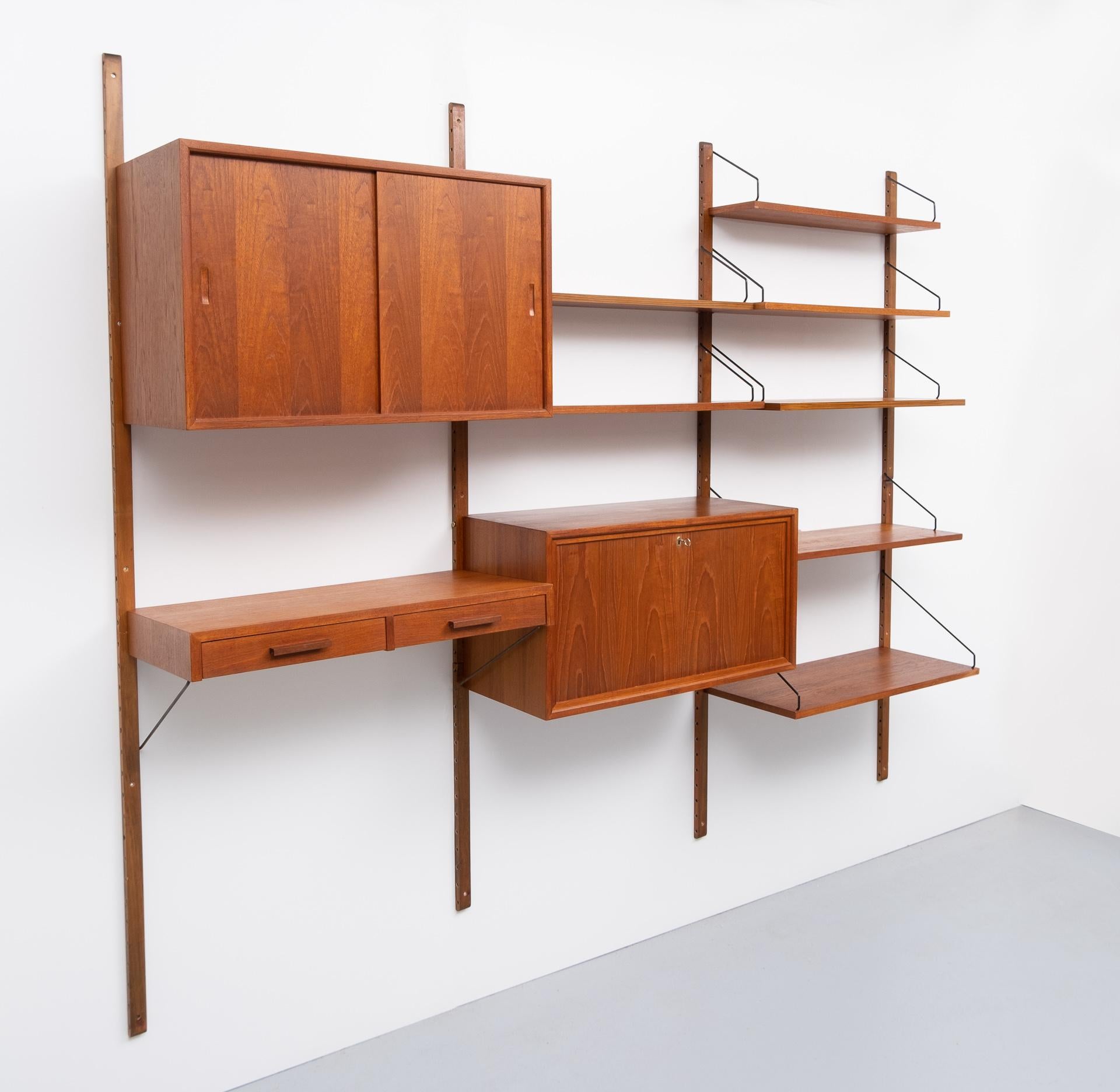A real design Classic, this Teak floating wall system. Design by Poul Cadovius for Cado Denmark. 
Consisting of: One cabinet with sliding doors, One with a beautiful writing interior, a little block 
with two drawers, and seven shelves in