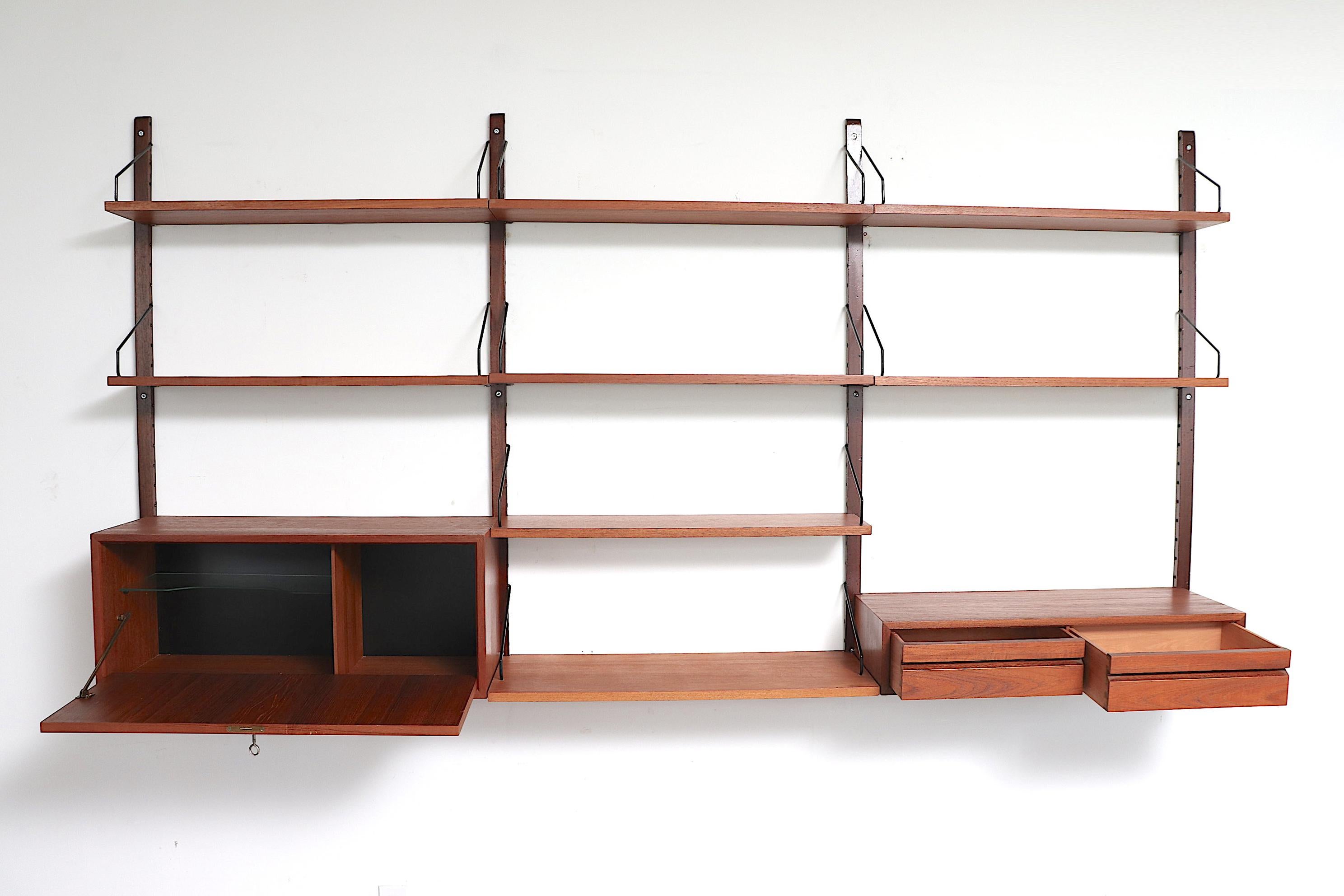Beautiful three-section Poul Cadovius wall unit with drop-down cabinet including a key, multiple shelves and double drawer storage. Simplistic, versatile and practical with gorgeous teak tone. In original condition with minimal wear and scratches
