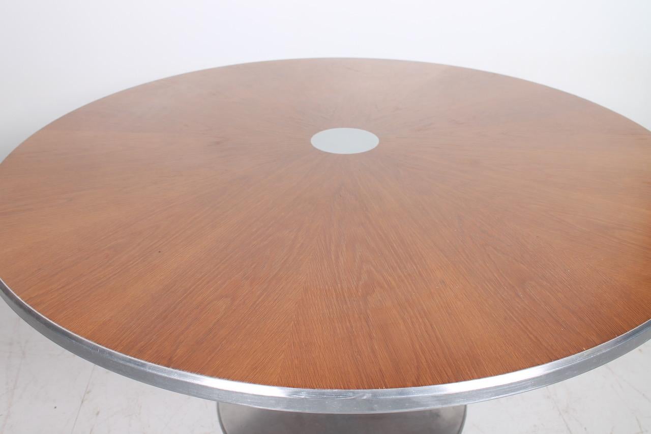 Large round dining table with trumpet foot in metal and metal detail in the centre of the top. Designed and produced in Denmark by Poul Cadovious. 