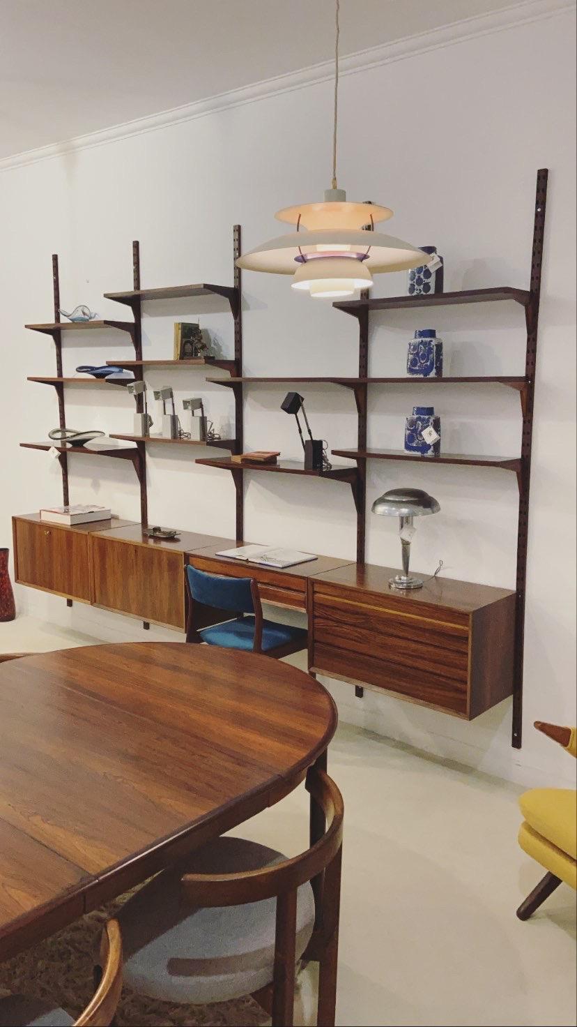 Modular shelving unit by Poul Cadovius, Cado, 1948. Besides the wall with 11 shelves, the system offers a huge storage space, with one small and 3 big cabinets with sliding doors and drawers. The system has been restored and looks great again.