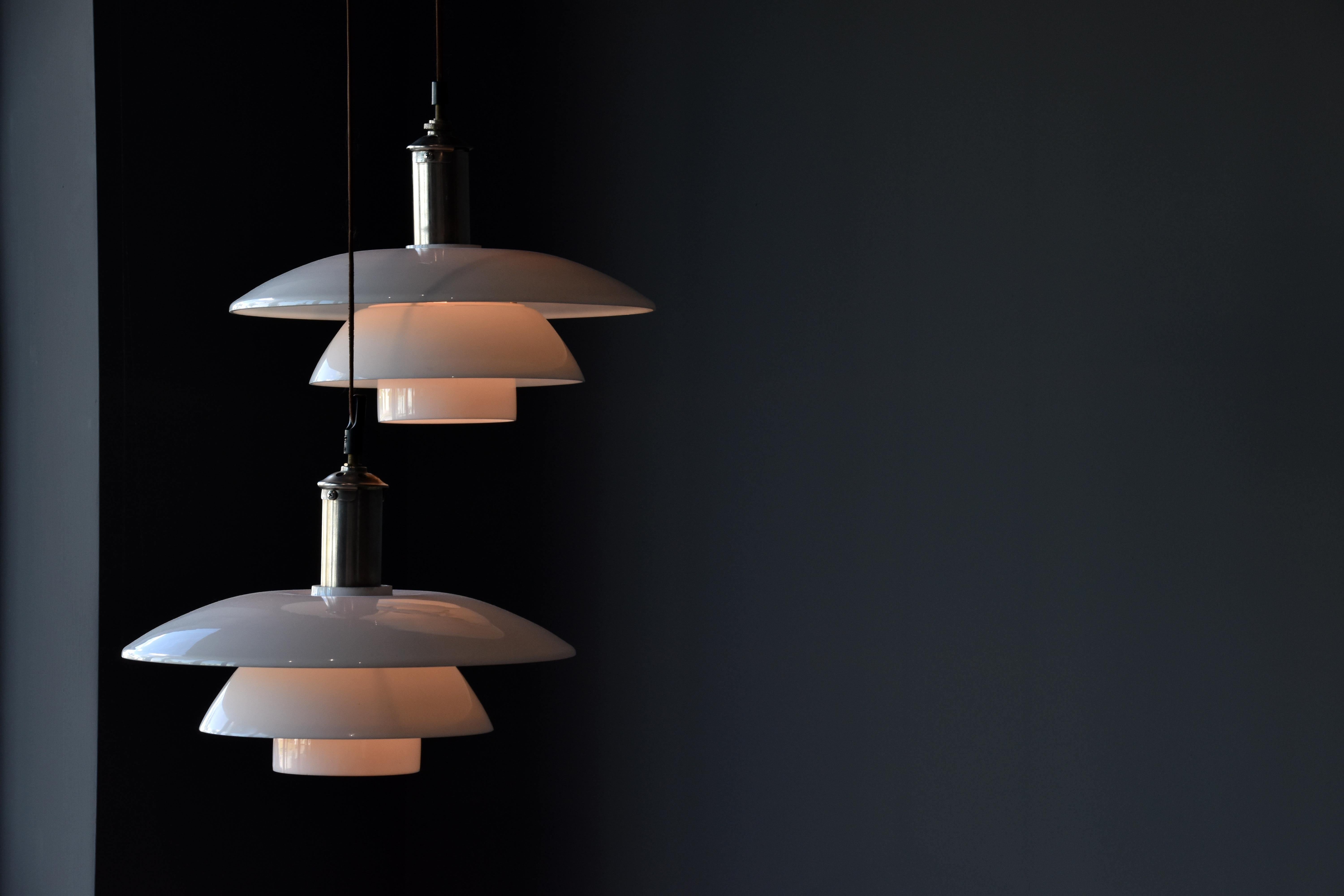 A pair of 1940s ceiling lamps or pendants designed by Poul Henningsen and produced by Louis Poulsen. Nickel-plated metal and 4/4 type shades of opaque glass.

Other Scandinavian lighting designers include Paavo Tynell, Arne Jacobsen, Carl-Axel