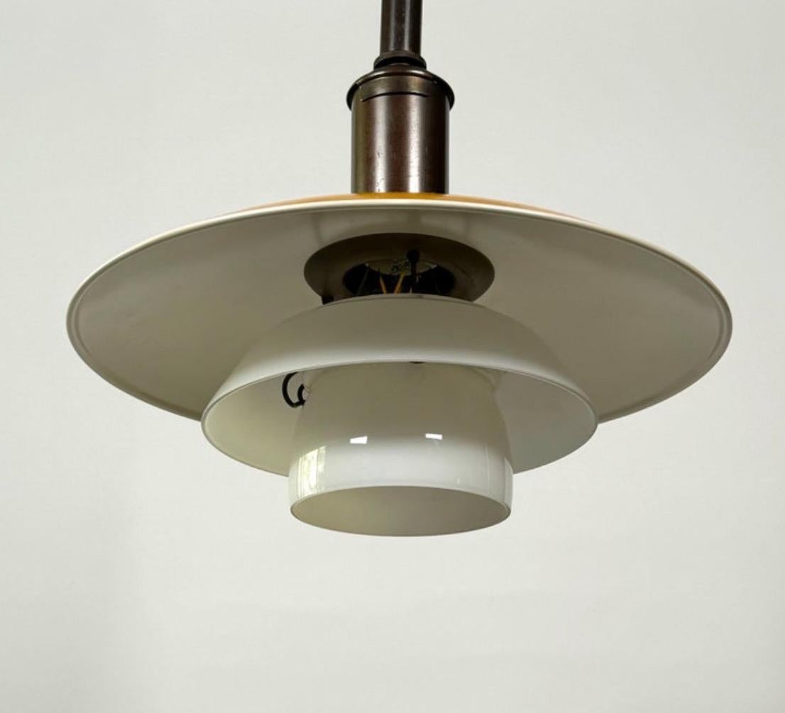 Classic design lamp by Poul Henningsen for Louis Poulsen. Lacquered yellow top shade and opaline glass lower shades. Browned brass hardware and fabric-covered cord. A US plug has been added but this lamp can be also hard wired. Made in Denmark,