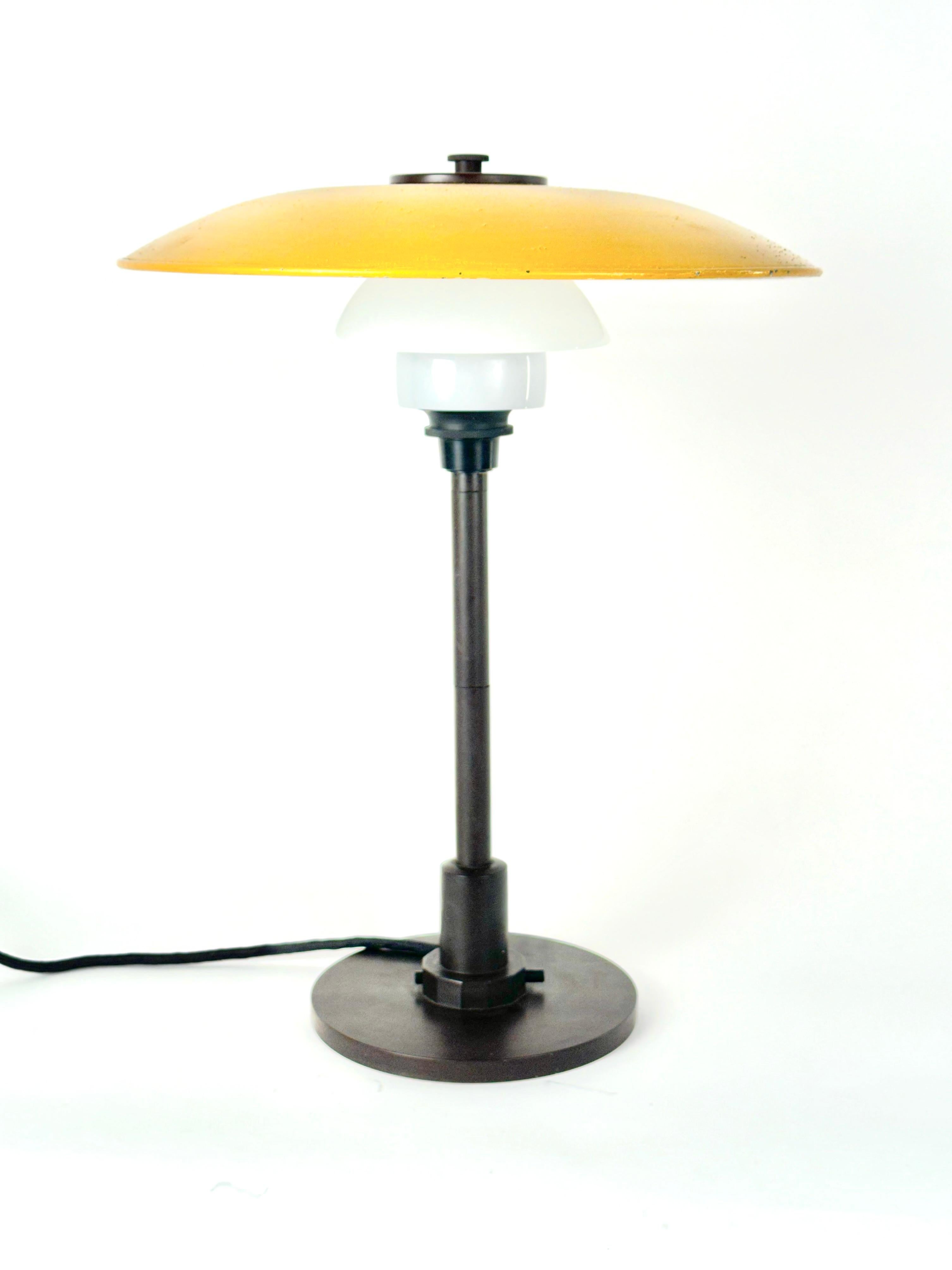 A vintage table lamp designed by Poul Henningsen and edited by Louis Poulsen on the 70s. Model 3 1/2/2 1/2 Isolation lamp. Bakelite table lamp, with yellow lacquered zinc top shade and multilayer opal glass middle and lower shade.
Literature: