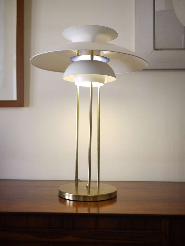 A desk lamp designed by Poul Henningsen and edited by Louis Poulson in 1960.Three brass supports on a brass base and white painted metal shades. Bleu inner ring and red top.