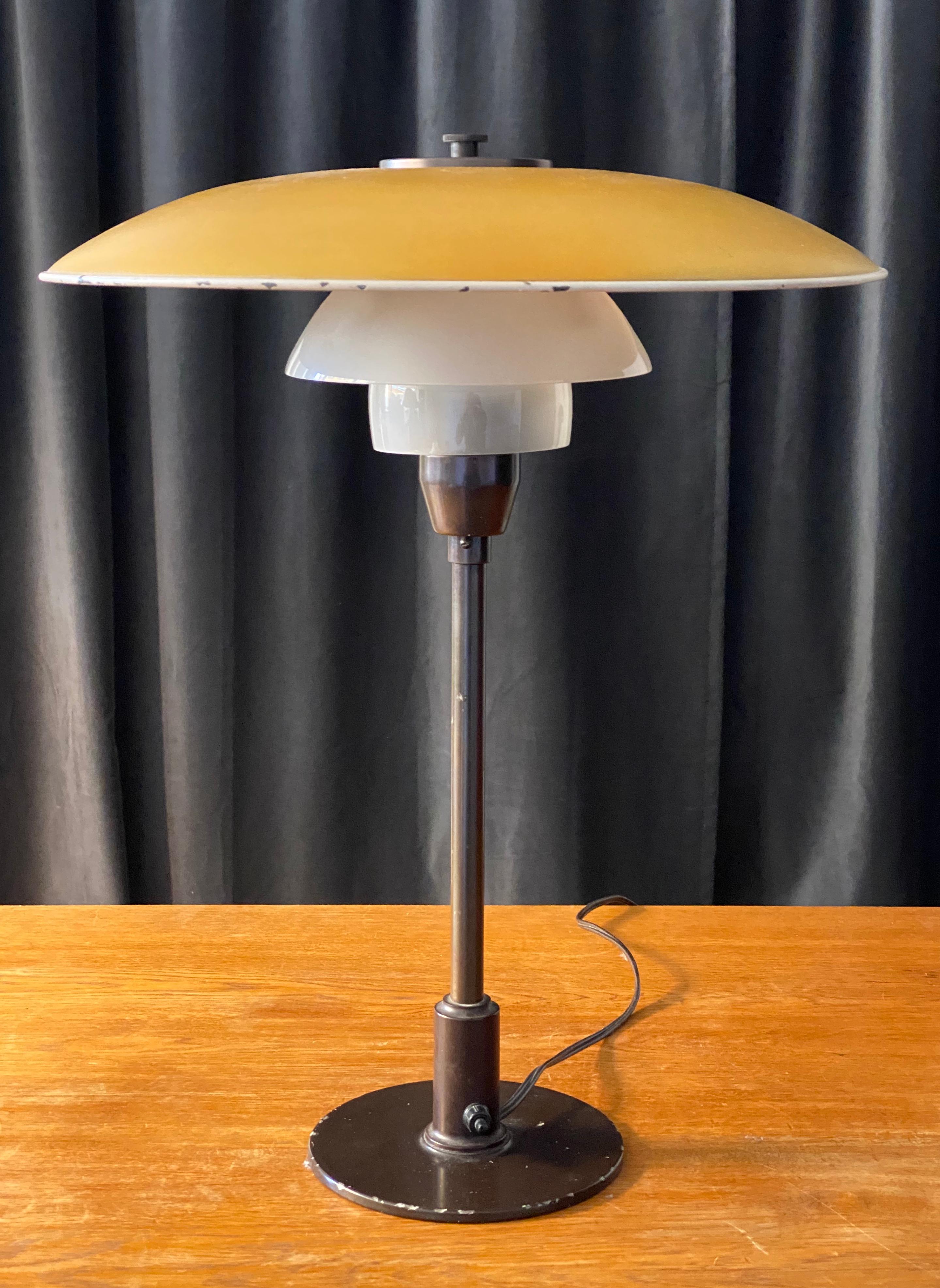 A table lamp designed by Poul Henningsen. Produced by Louis Poulsen. With its original glass and metal shades. Browned brass and bakelite. 

Other designers of the period include Kaare Klint, Paavo Tynell, Lisa Johansson Pape, and Alvar Aalto.