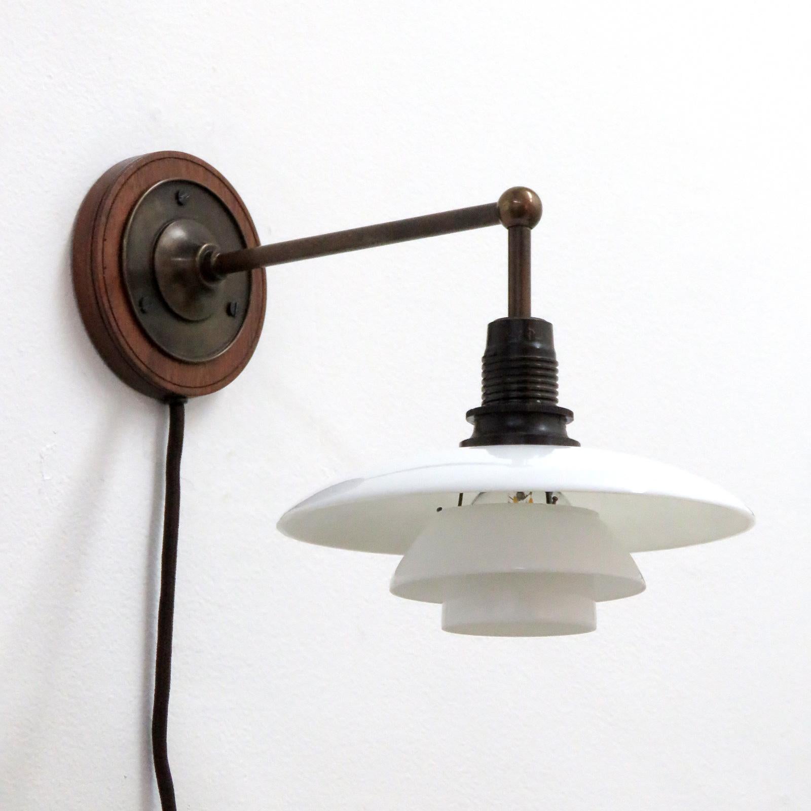 Wonderful PH 2/1 wall lights by Poul Henningsen for Louis Poulsen, 1930, three opaline glass shades and frosted diffuser on a brass arm with oak wall mount, wired as plug-in version with newer cloth wire to match the original, bakelit socket and