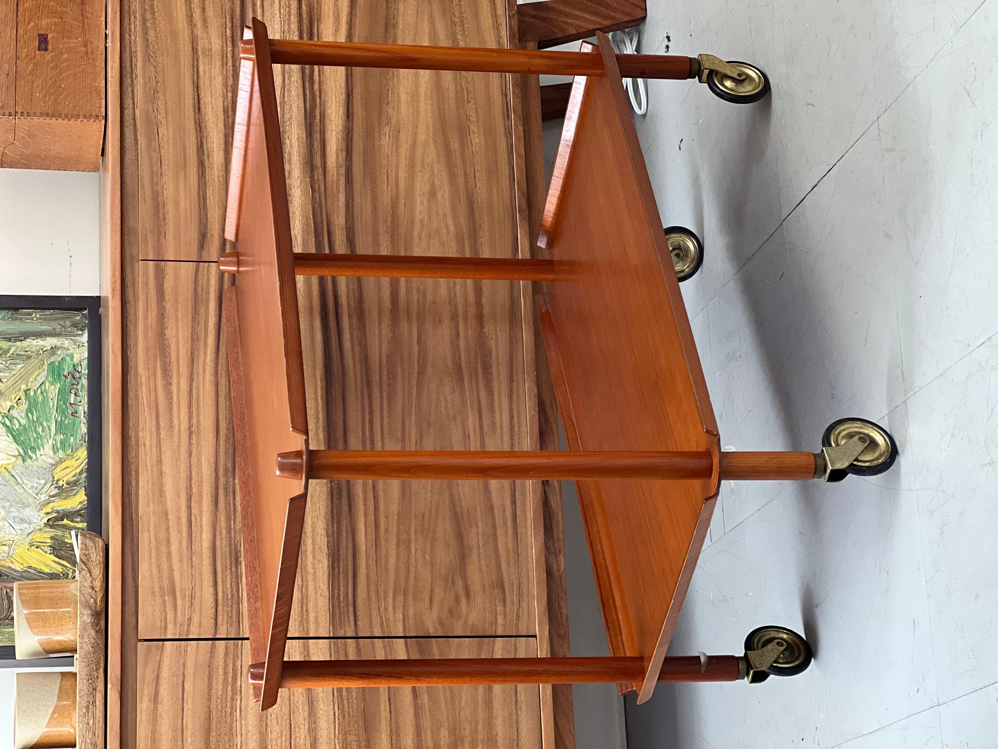 Chariot à thé roulant vintage danois  MCM avec roulettes ton laiton
Rehaussez votre espace avec ce superbe chariot de bar en teck de style moderne du milieu du siècle, une pièce intemporelle d'inspiration danoise parfaite pour recevoir ou ajouter un