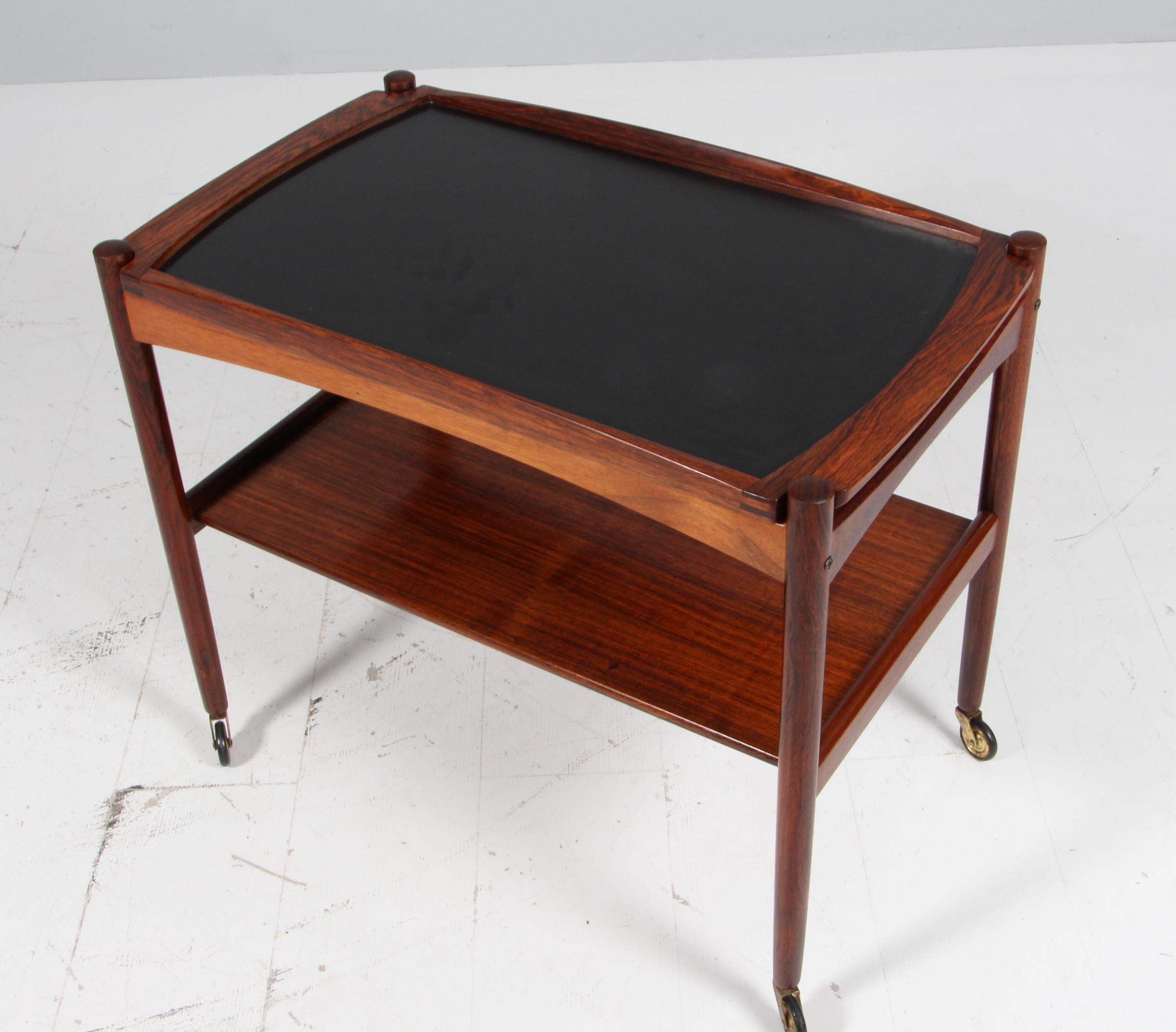 Poul Hundevad bar cart with raised sides. And top of formica.

Brass wheels.

Made by Poul Hundevad.