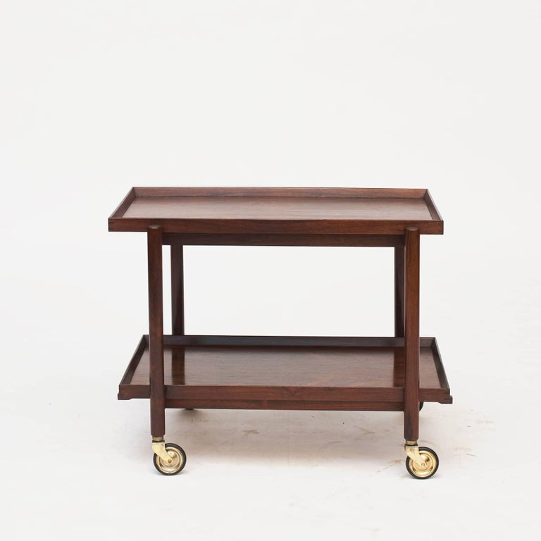 Poul Hundevad design.
Rosewood rolling cart featuring two tray tiers which can be removed and rearranged into a larger serving top.

Designed by Poul Hundevad for Hundevad & Co, Denmark 1960's.
Good overall condition.
