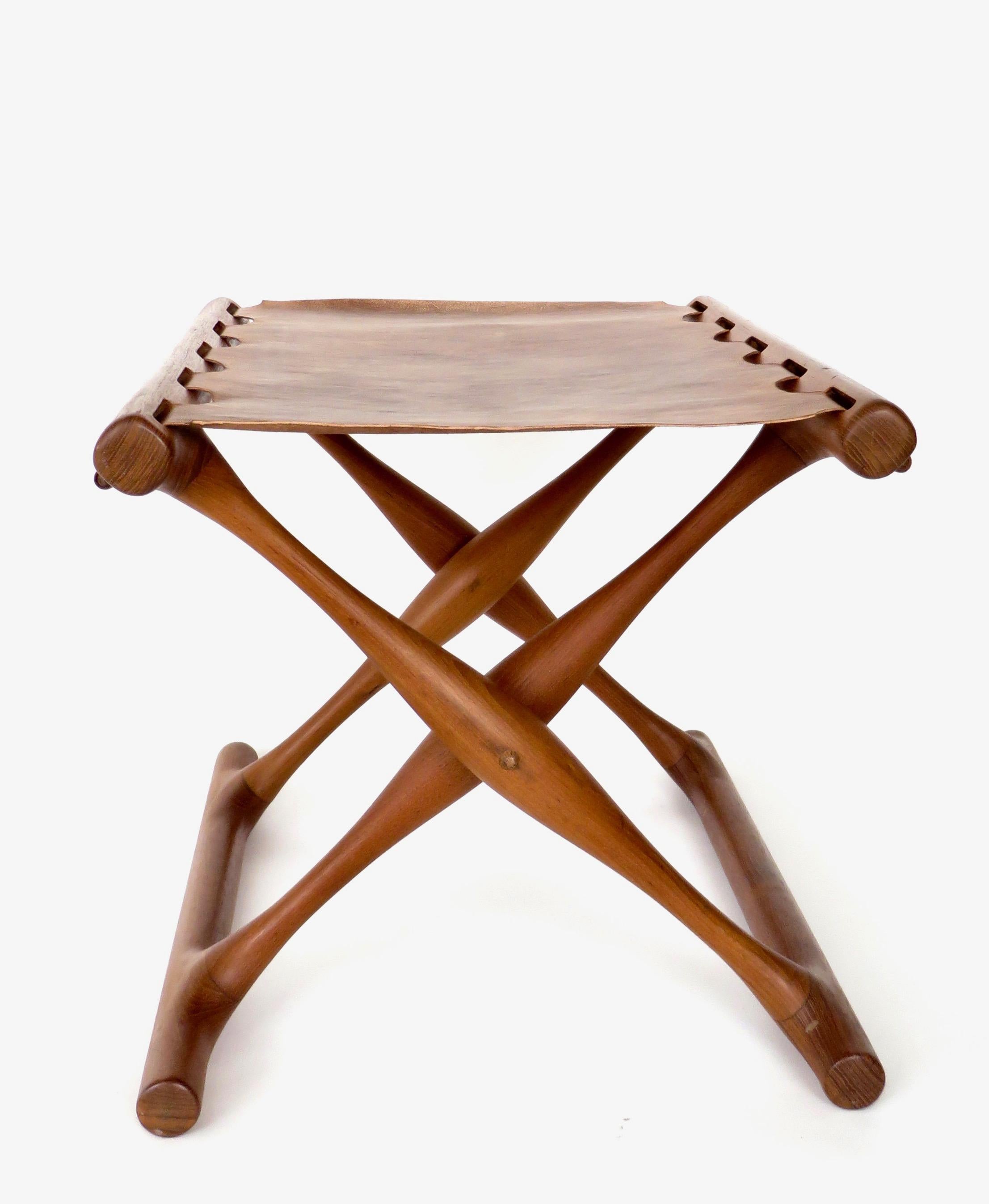 Danish modern teak and leather folding stool by Poul Hundevad, Denmark, circa 1960s. The leather has been replaced as the original leather was very fragile and tore but still available to include in the purchase. 
This sculptural folding stool is