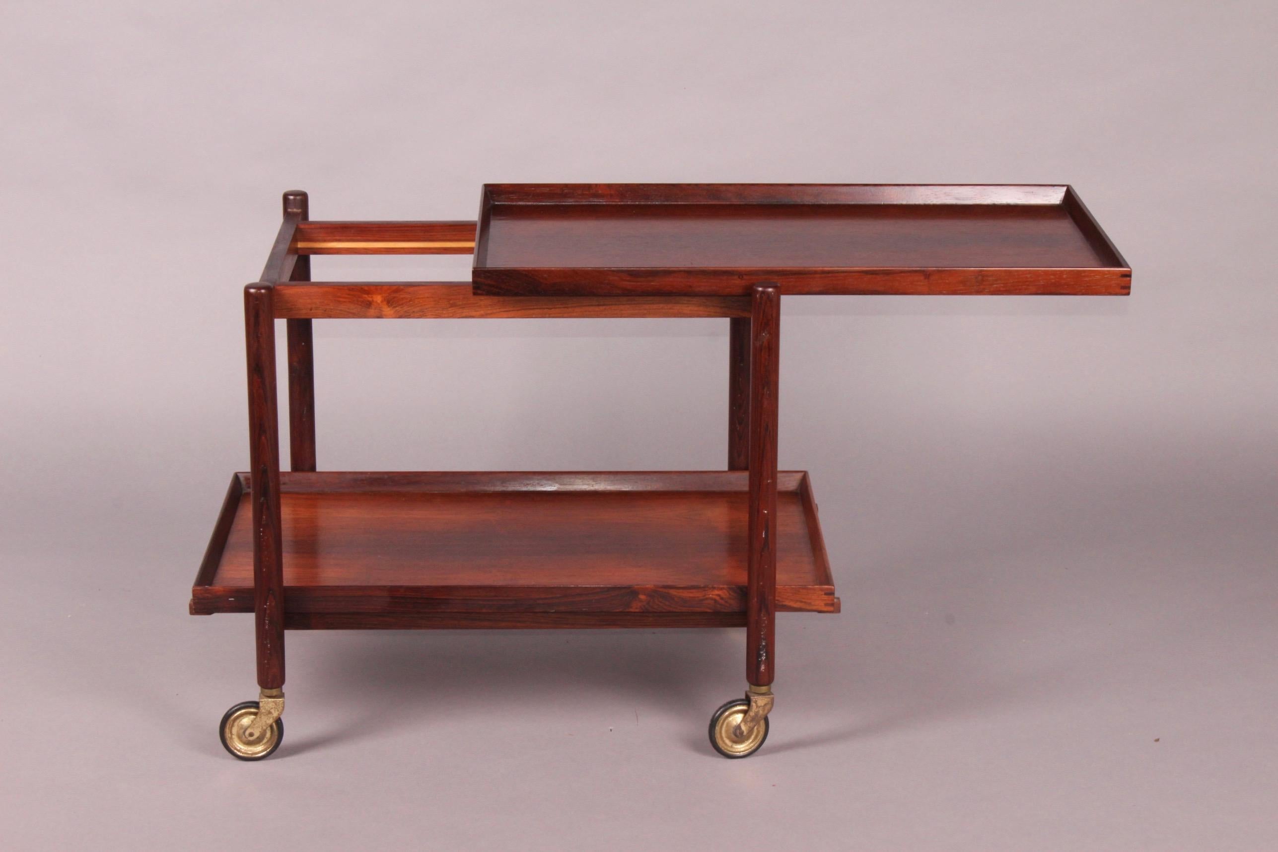 Vintage Poul Hundevad rosewood Mid-Century bar cart. This unique design allows for the bottom tray to be removed and added to the top to expand the serving surface. Brass and rubber casters. Expands to 60 inches when bottom shelf is removed and