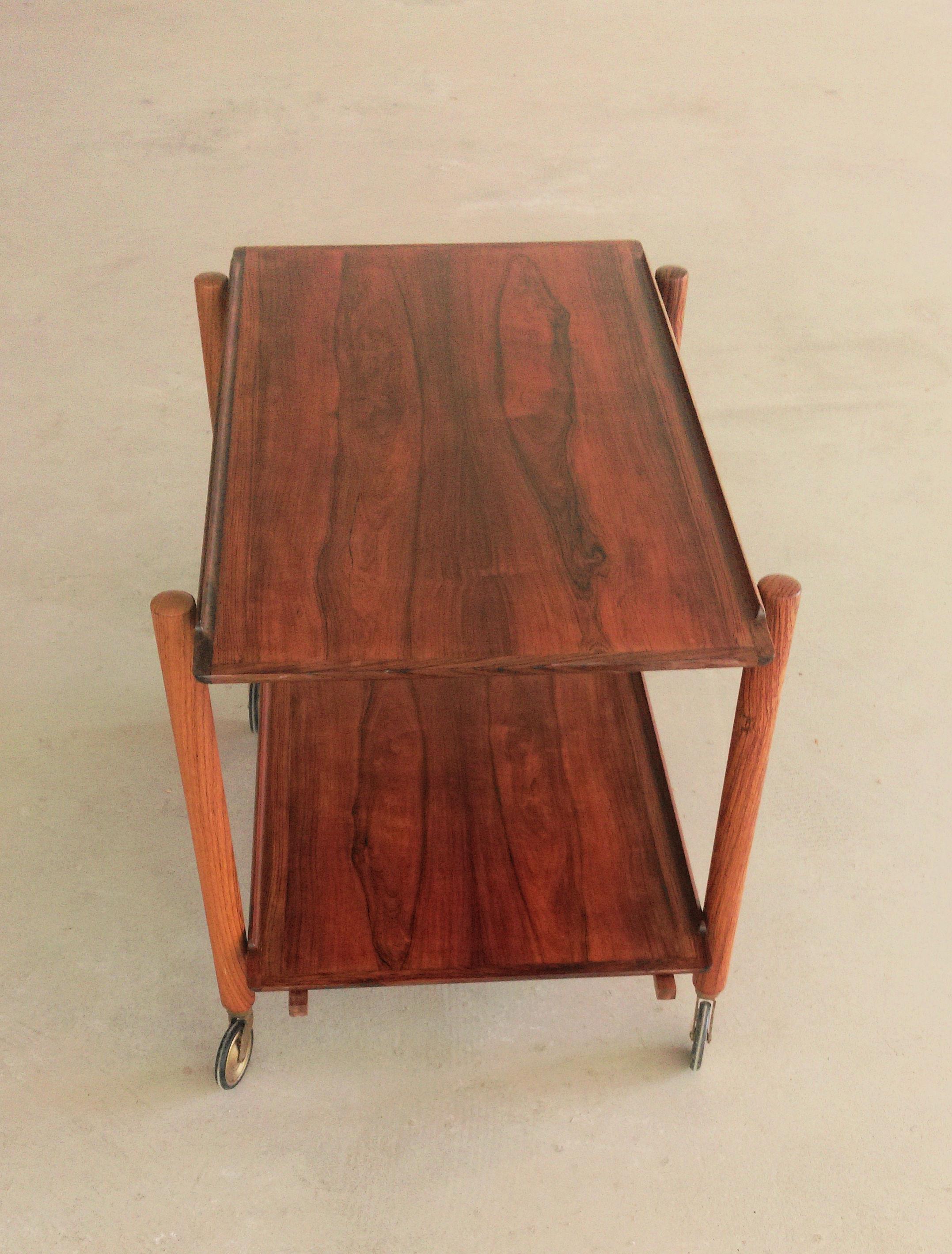 1960s Poul Hundevad Danish modular two-tiered rosewood bar cart

The flexible bar table features a unique combination of organic shapes, excellent craftsmanship and a very flexible design that enables the four wheeled table to be used for numerous