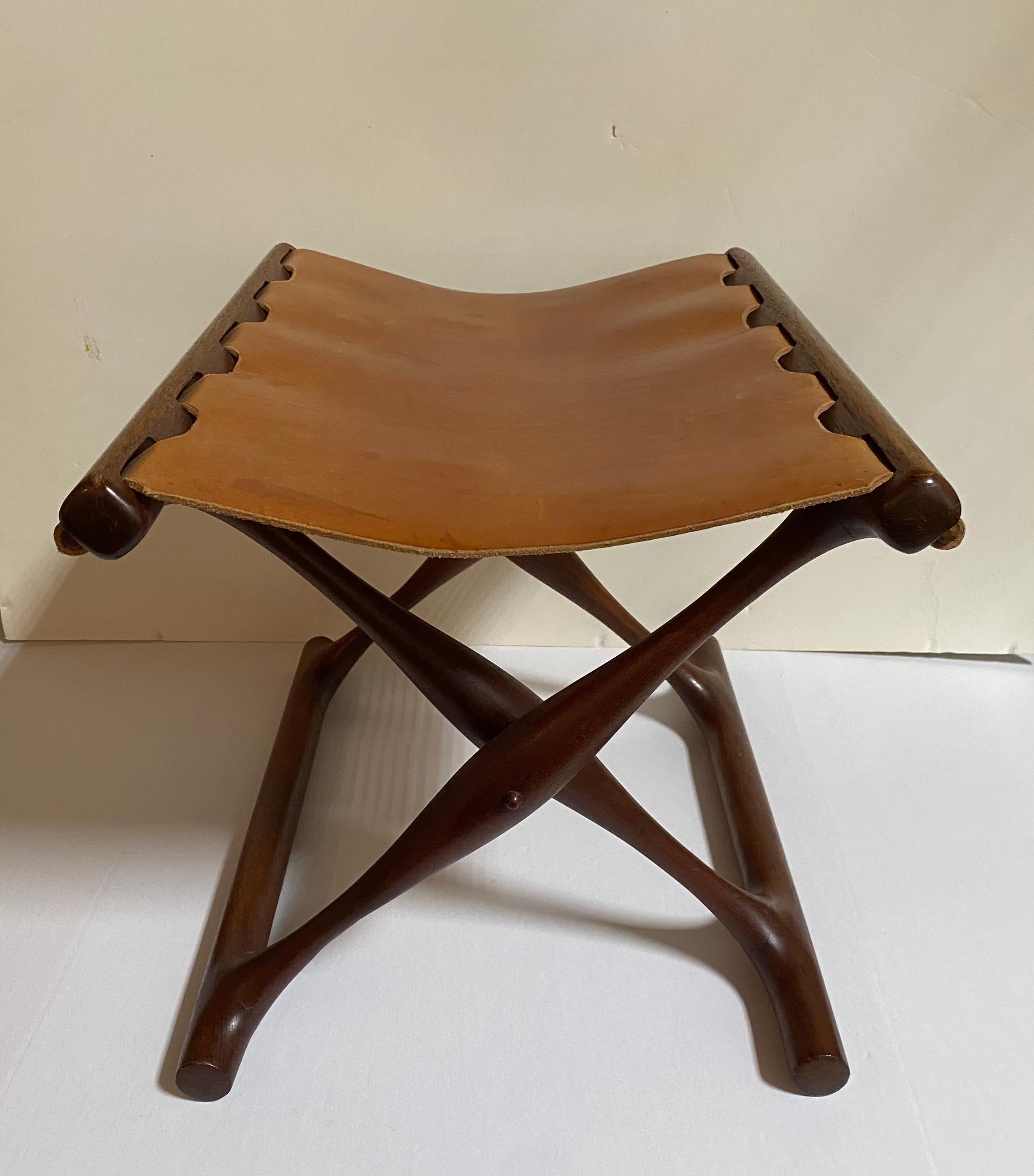 Wood and Cognac leather folding stool designed by Poul Hundevad. circa 1950. Unsigned. Base in very good vintage condition with original leather seat.

Hundevad based his design on this folding stool on an original that was found in a grave dating