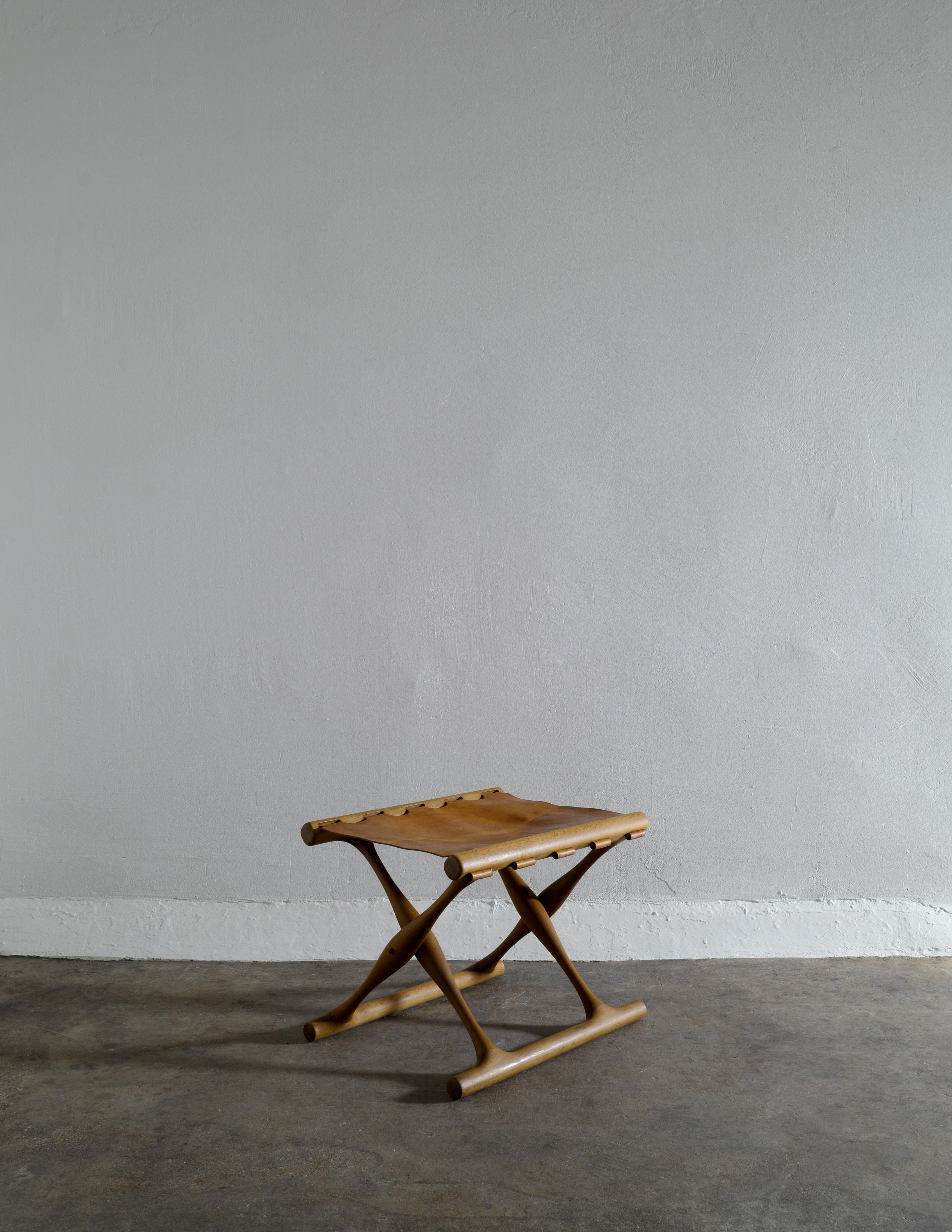 Rare and great example of Poul Hundevad's iconic “Guldhøj” folding stool in beech and leather. In good and original vintage condition showing some signs from age and use. The original sticker is still attached under neath the leather seating.