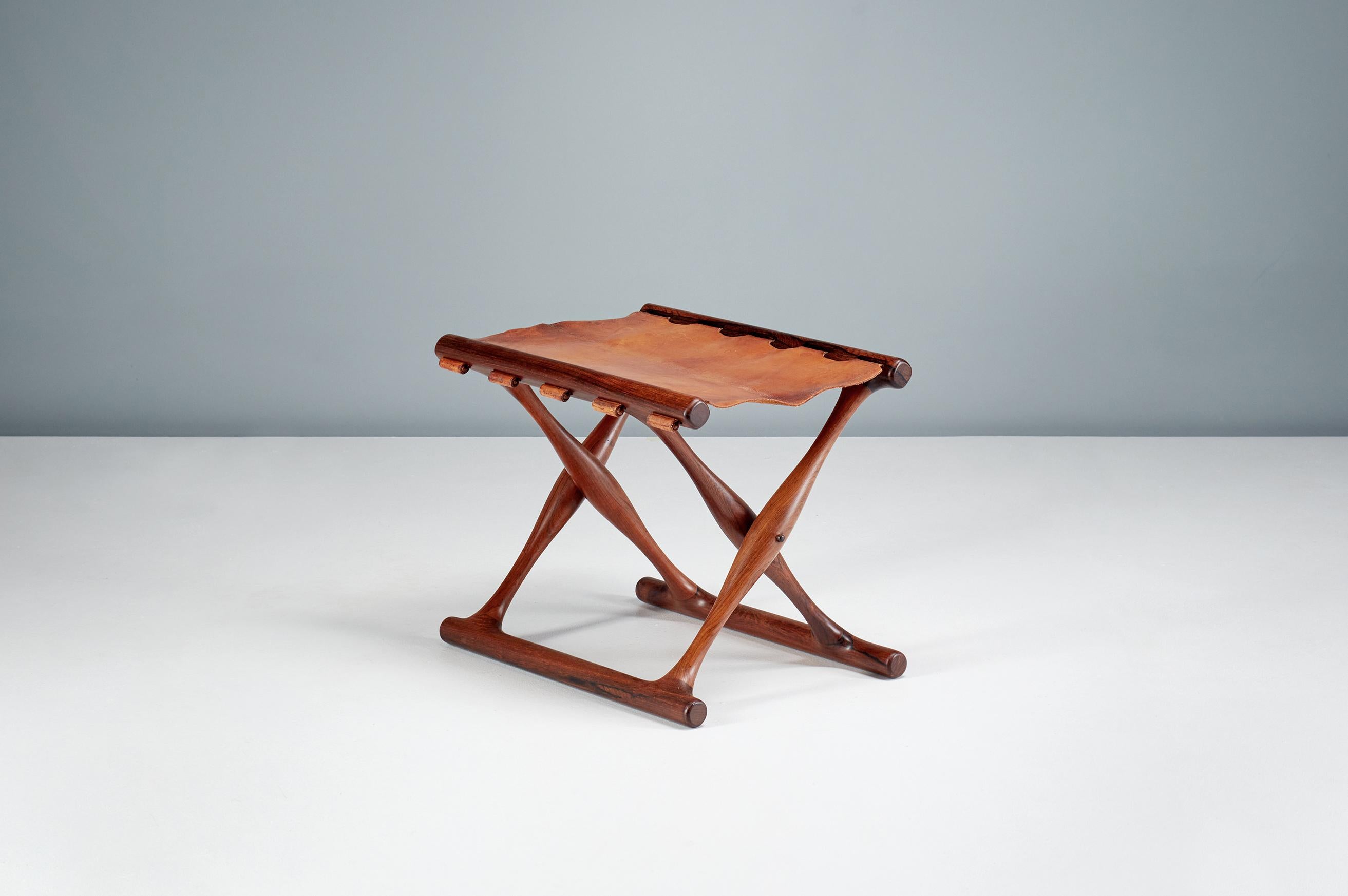 Poul Hundevad - Guldhoj Folding Stool, 1948

The iconic model 41 folding stool in beautiful rosewood with original, patinated cognac brown saddle leather seat. The Guldhoj stool was designed as a replica of a Bronze Age artefact found in Vamdrup,