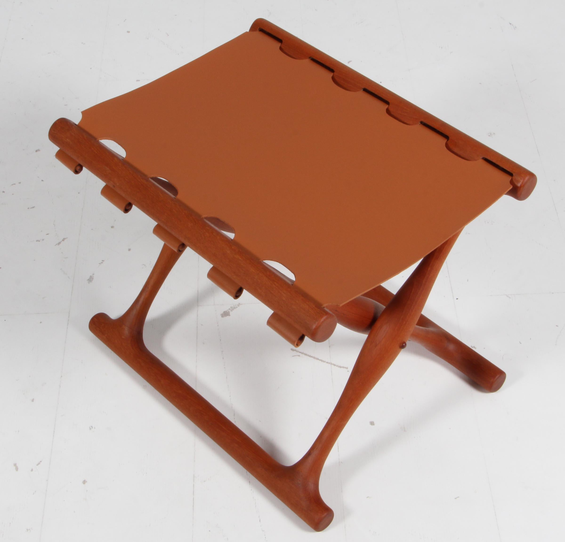 The iconic model 41 folding stool in beautifully aged Danish teak new cognac brown saddle leather seat. The Guldhoj stool was designed as a replica of a Bronze Age artefact found in Vamdrup, Denmark that dates back to 1300 BC. The stool is therefore