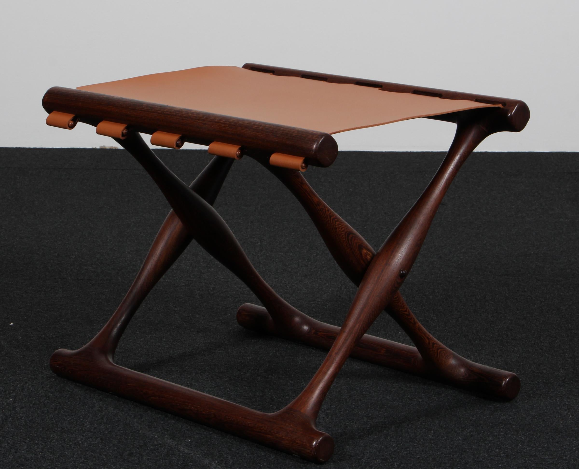 Der ikonische Klapphocker Modell 41 in wunderschön gealterter dänischer Wenge, neuer Sitz aus cognacbraunem Sattelleder. Der Guldhoj-Hocker wurde als Nachbildung eines Artefakts aus der Bronzezeit entworfen, das im dänischen Vamdrup gefunden wurde