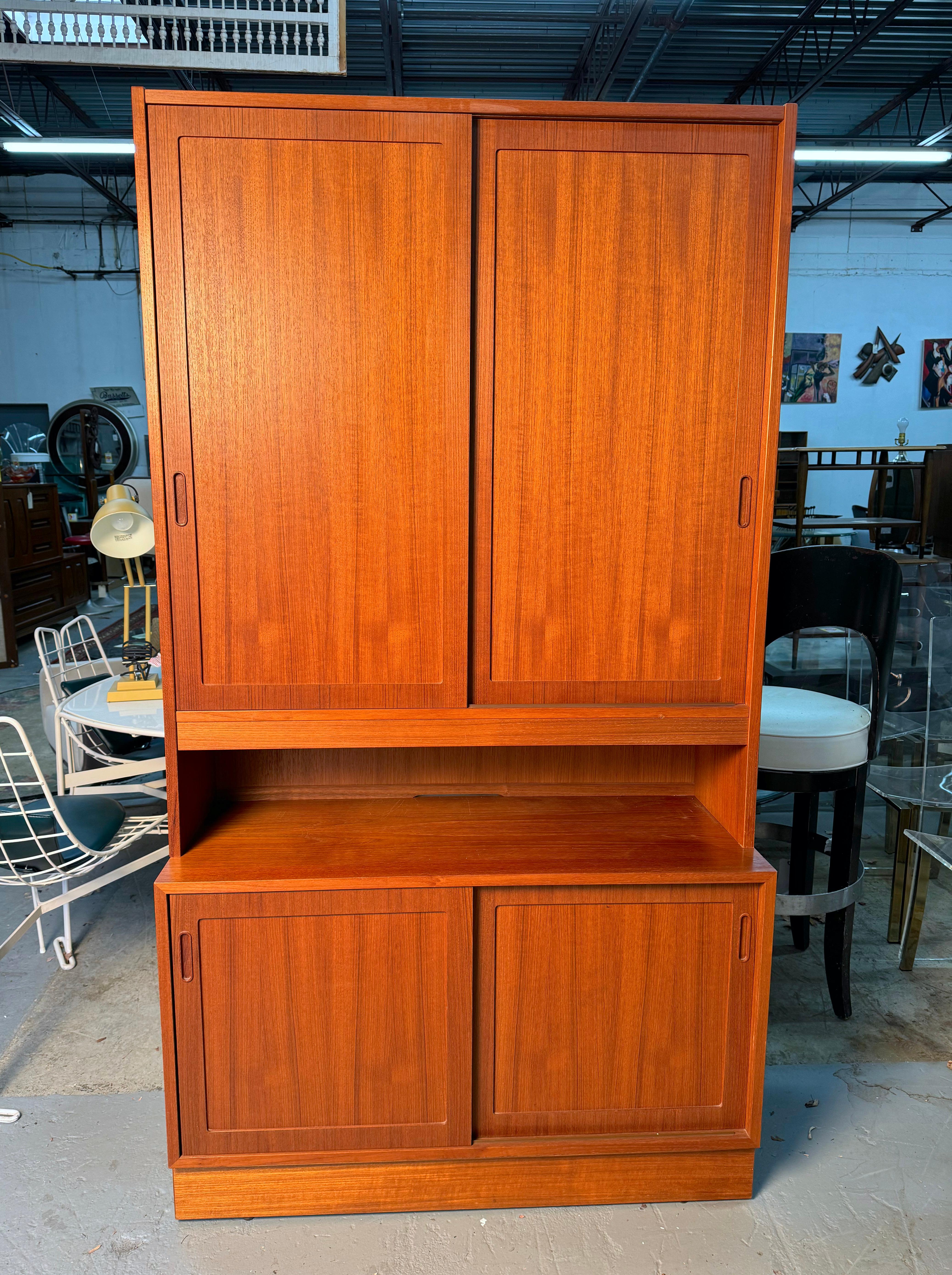 This stunning Poul Hundevad Mid Century Danish Teak Buffet and Hutch is a masterful example of timeless Scandinavian design. Crafted from rich teak wood, this versatile piece combines both style and function, featuring clean lines and a sleek,