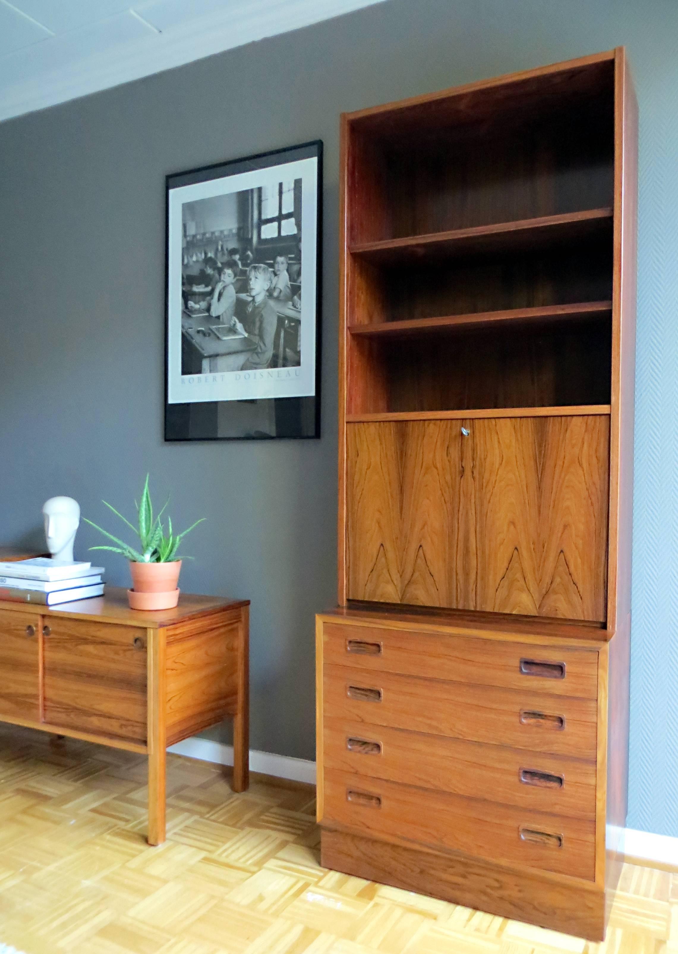 This vintage bookshelf was designed / manufactured in the early 1960s by Poul Hundevad & Co. in Denmark.
It is from two-part and can be used in many different ways as a secretaire, shelves and a chest or dresser.

The particularity of this wall unit