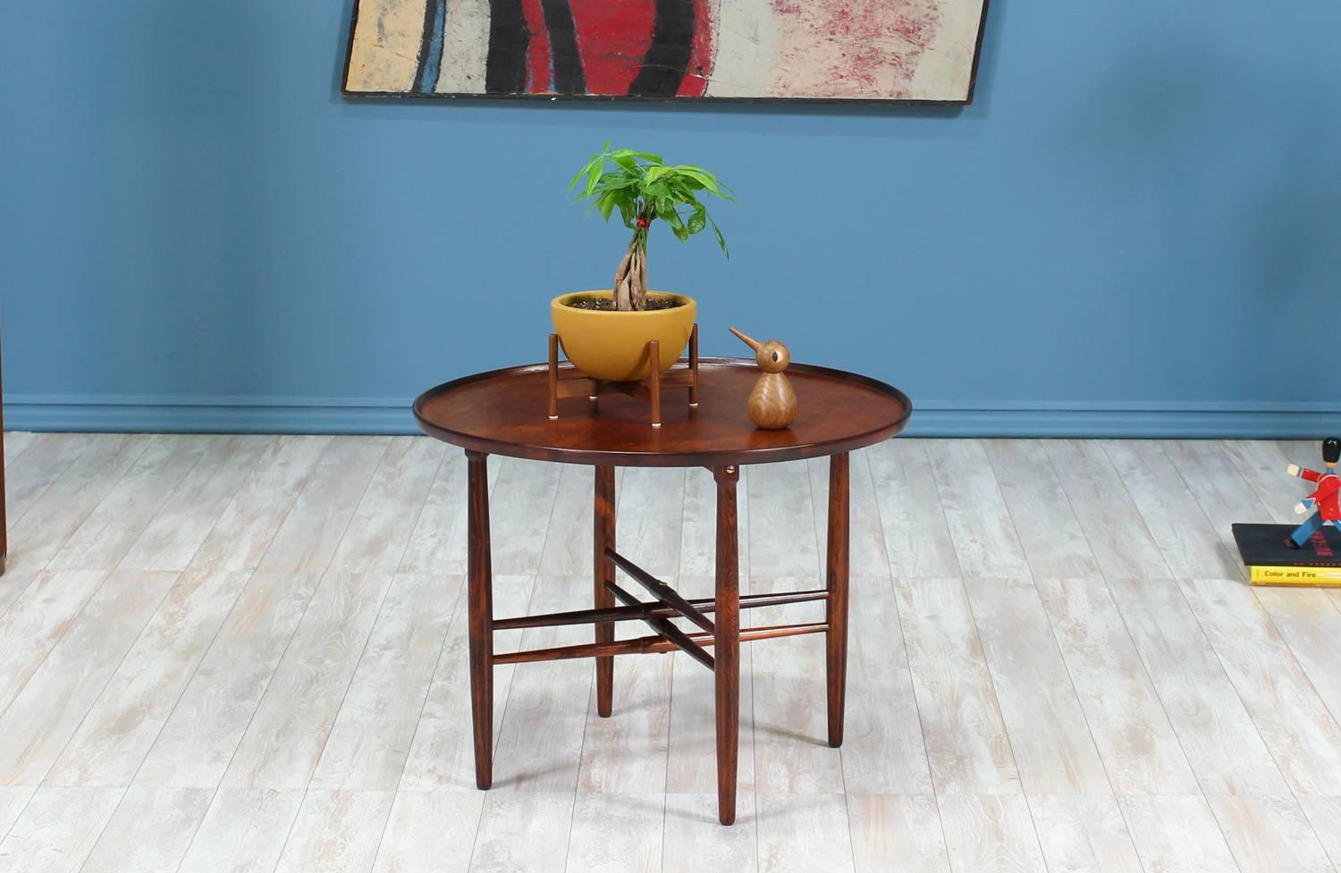 Side table designed by Poul Hundevad for Vamdrup Stolefabrik in Denmark circa 1950’s. This elegant side table is made of rosewood featuring a double “X” base and a round top with a raised lip border and beautiful grain patterns.