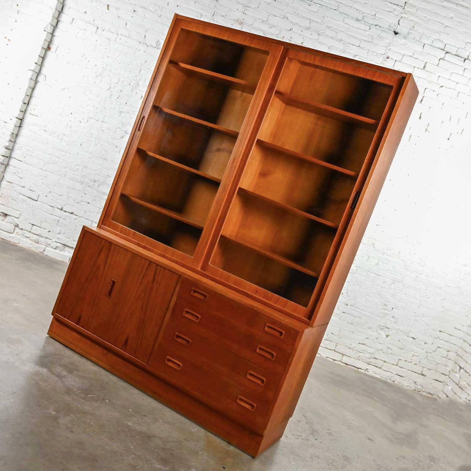 Lovely Poul Hundevad for Hundevad & Co. Scandinavian Modern teak china hutch cabinet, display cabinet, or bookcase. Comprised of 2 pieces, a top hutch featuring bypass doors with glass inserts and four adjustable shelves and a bottom buffet with 4