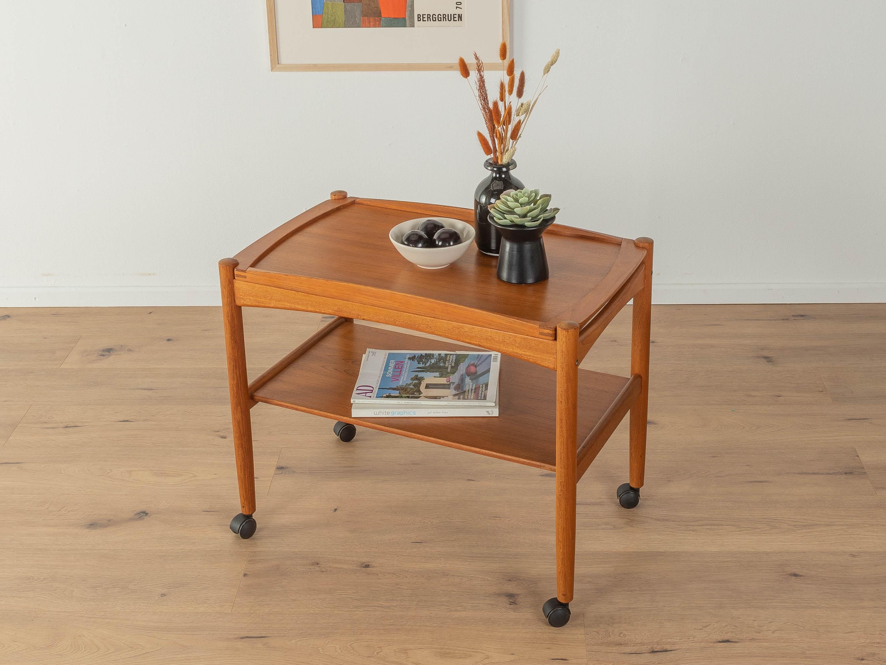 Classic serving trolley from the 1960s. Solid teak frame with two shelves in teak veneer and plastic castors. The upper shelf can be used as a tray.

Quality Features:
 Accomplished design: perfect proportions and visible attention to detail
