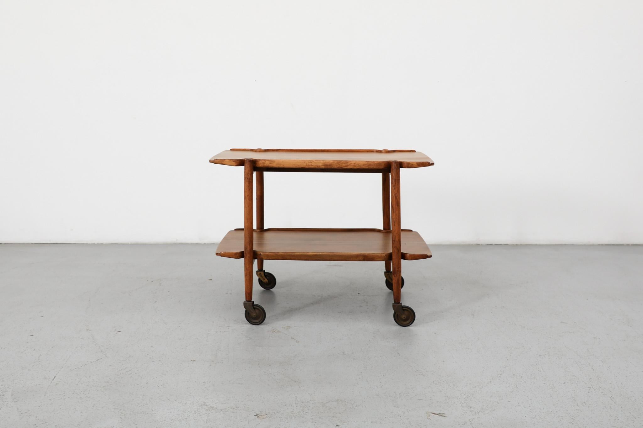 Graceful Danish serving cart showcases the organic aesthetic of Mid-Century Scandinavian design. Crafted in the distinctive style of Poul Hundevad, renowned for his sculptural approach to functional furniture, the piece exemplifies the harmonious