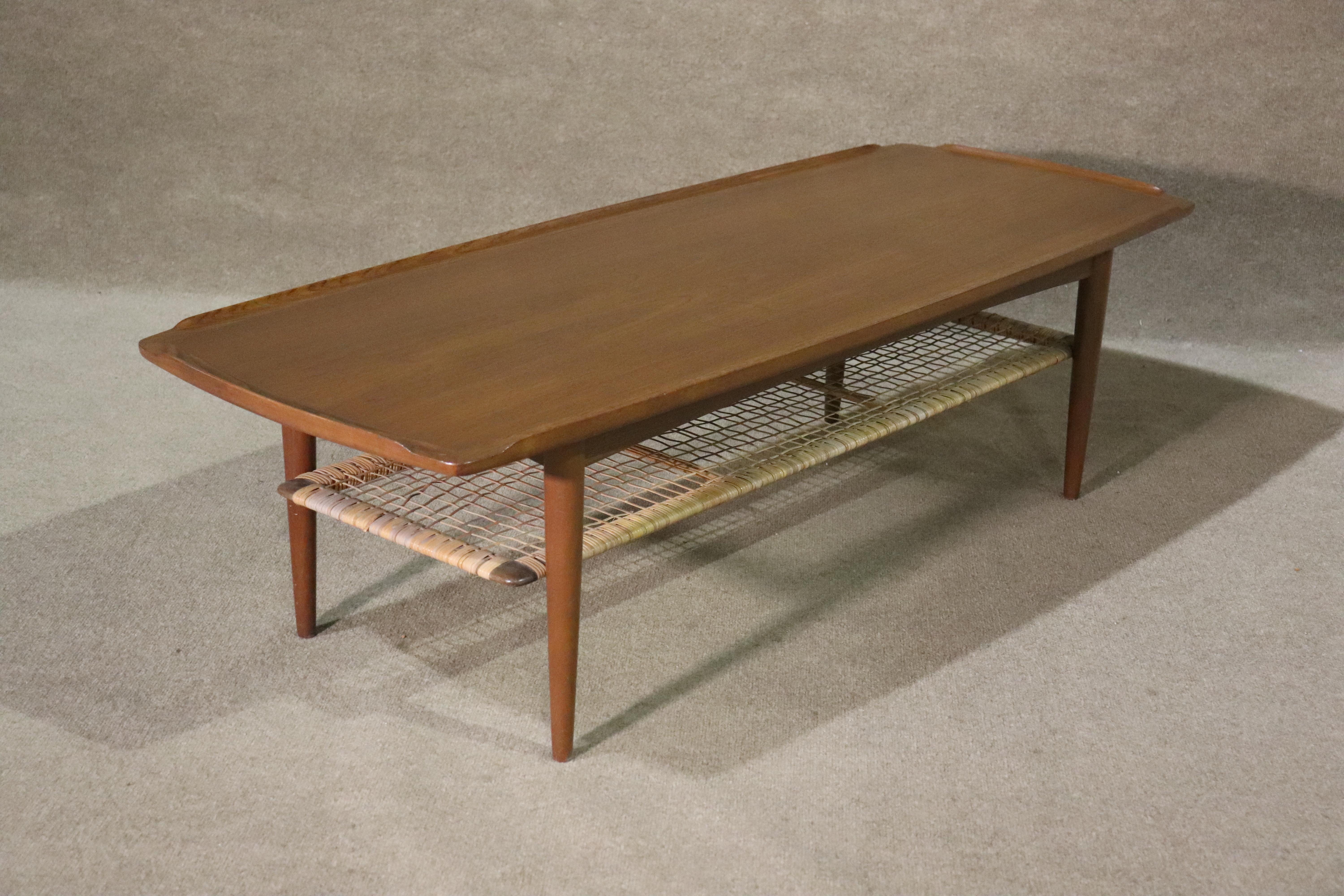 Danish coffee table designed by Poul Jensen for Selig. Great mid-century design with turned edges and woven shelf.
Please confirm location NY or NJ