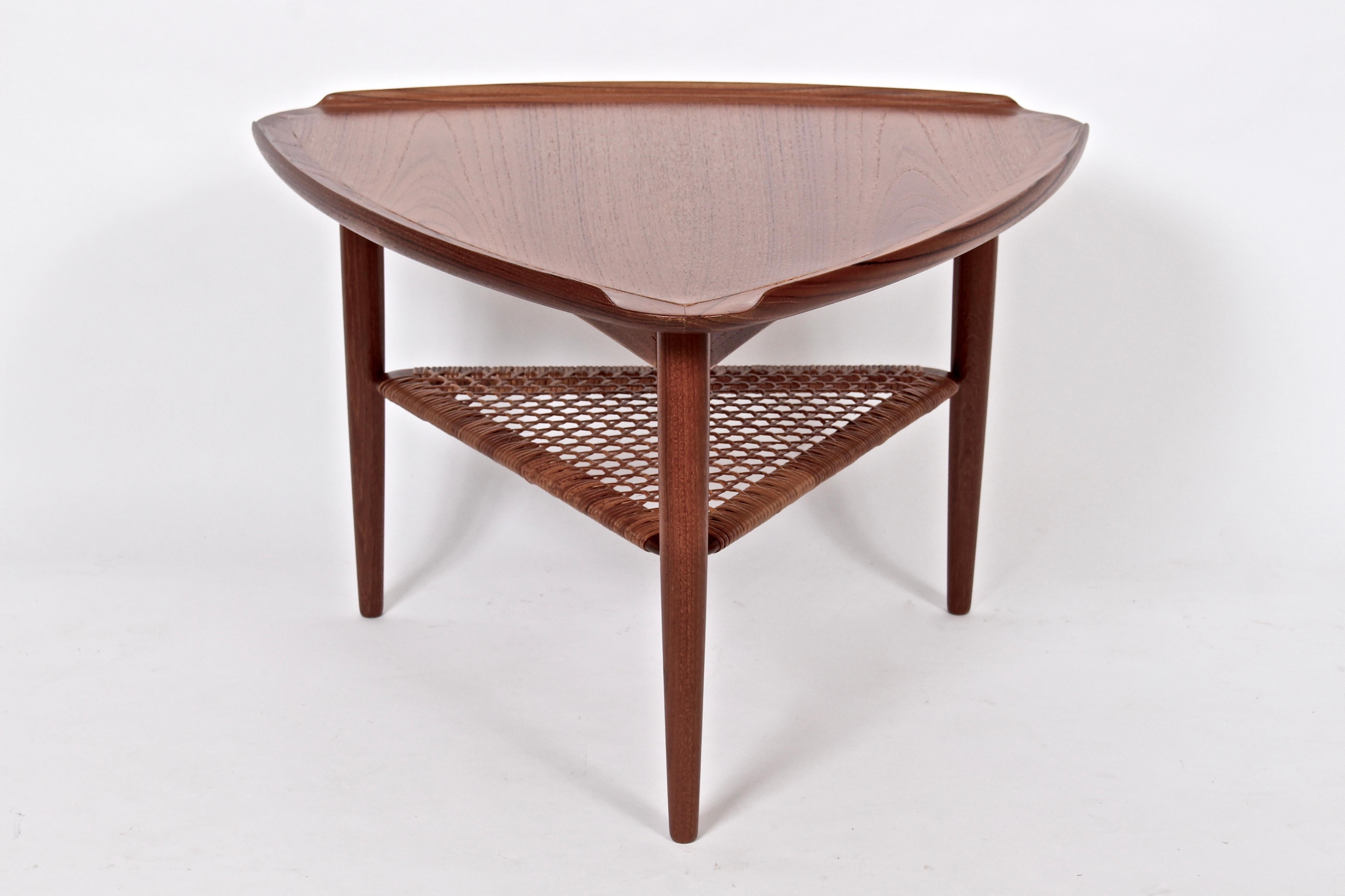 Danish Modern Poul Jensen for Selig Importers Teak & Woven Cane guitar pick coffee table, occasional table, side table. Featuring a smooth, seamed and lipped triangular Teak surface, braced turned solid Teak legs with woven Cane shelf. Legs 21 D x
