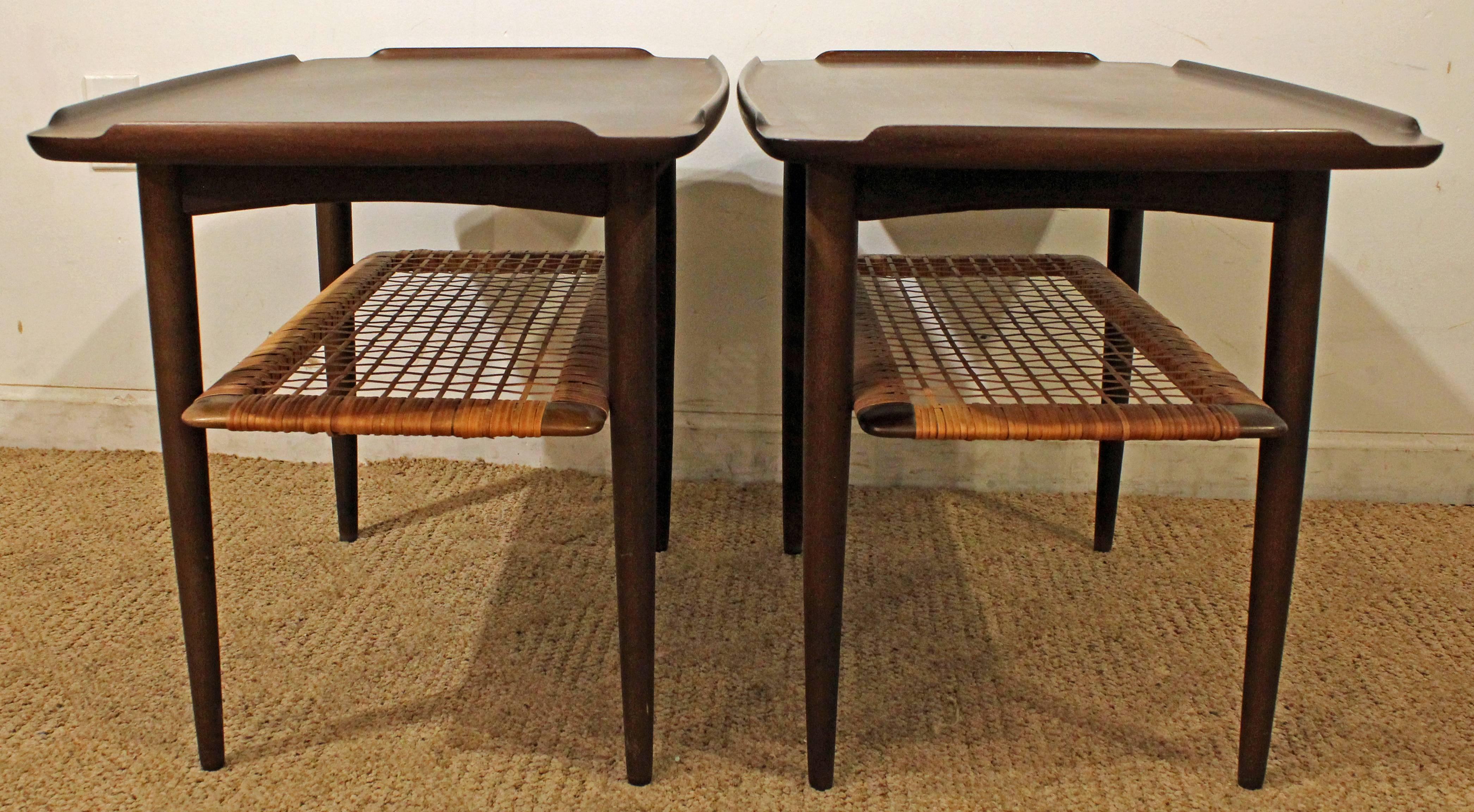 These were designed by Poul Jensen for Selig. The tables are made of teak. They have an upturned raised edge on all four sides and a caned shelf. They have been completely restored.