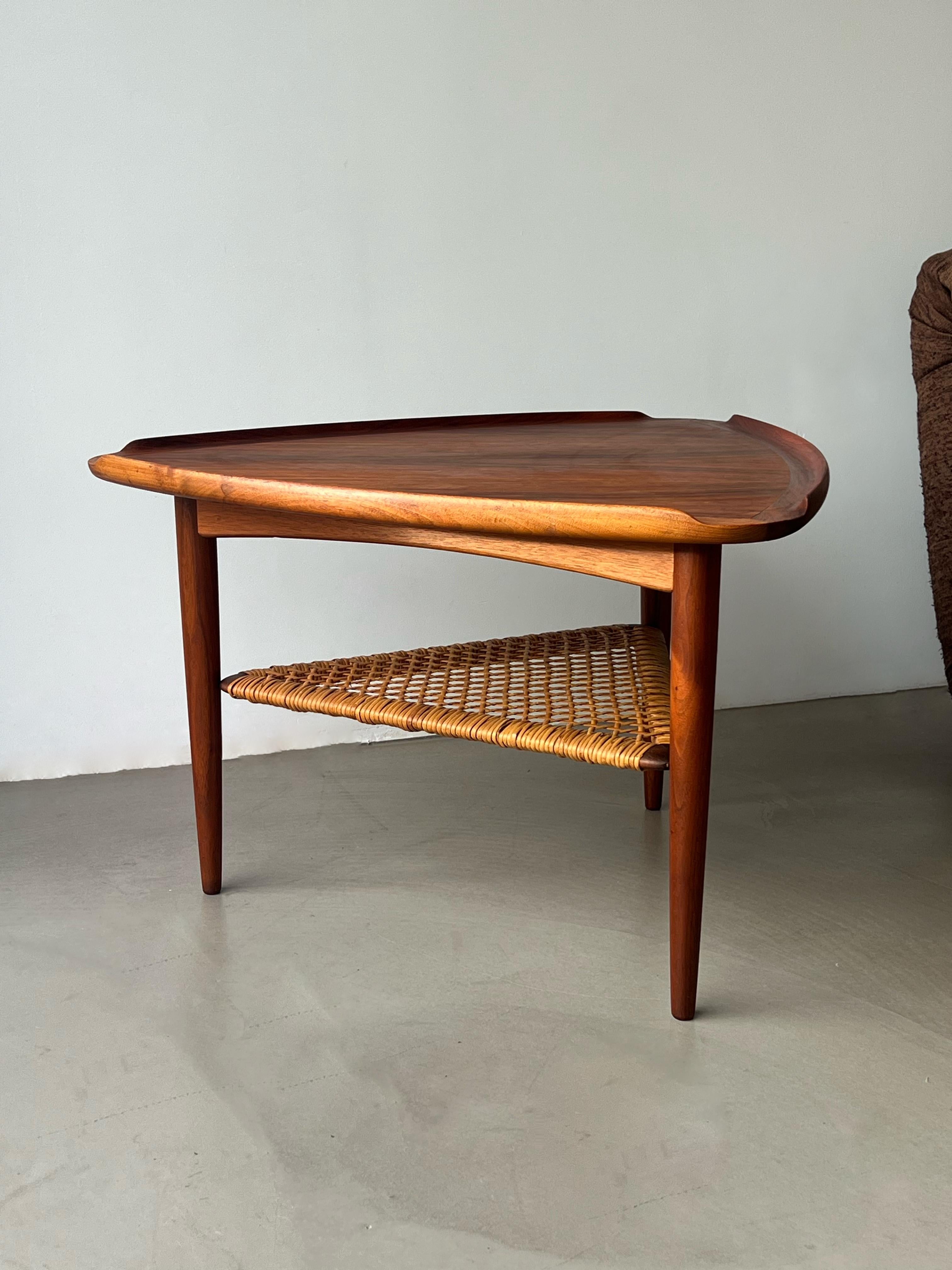 This is a stunning example of mid-century modern design by Poul Jensen for Selig – the iconic 'Guitar Pick' table. Crafted in Denmark during the 1960s, this piece features a beautifully sculpted triangular top and a lower shelf woven from cane,